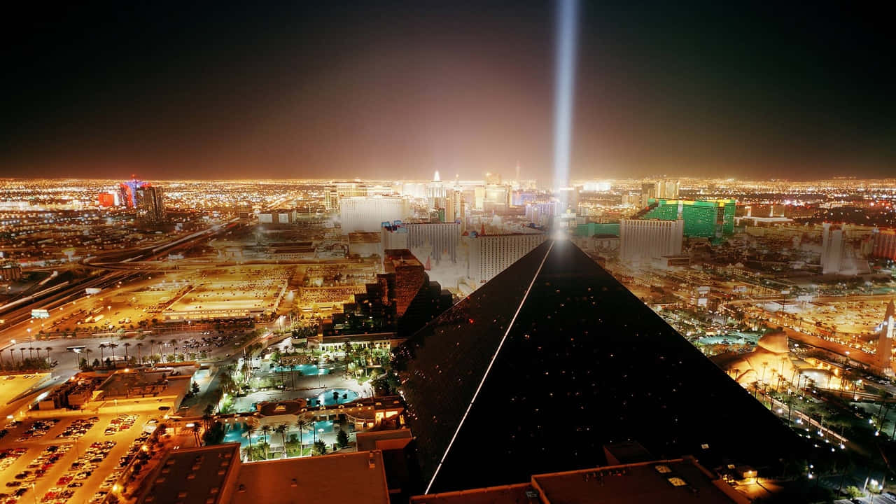 720p Las Vegas 桌布 壁紙 — 拉斯維加斯令人驚嘆的夜間空中景觀，展示了盧克索金字塔及其標誌性的光束，劃破閃爍城市景觀上方的天空。