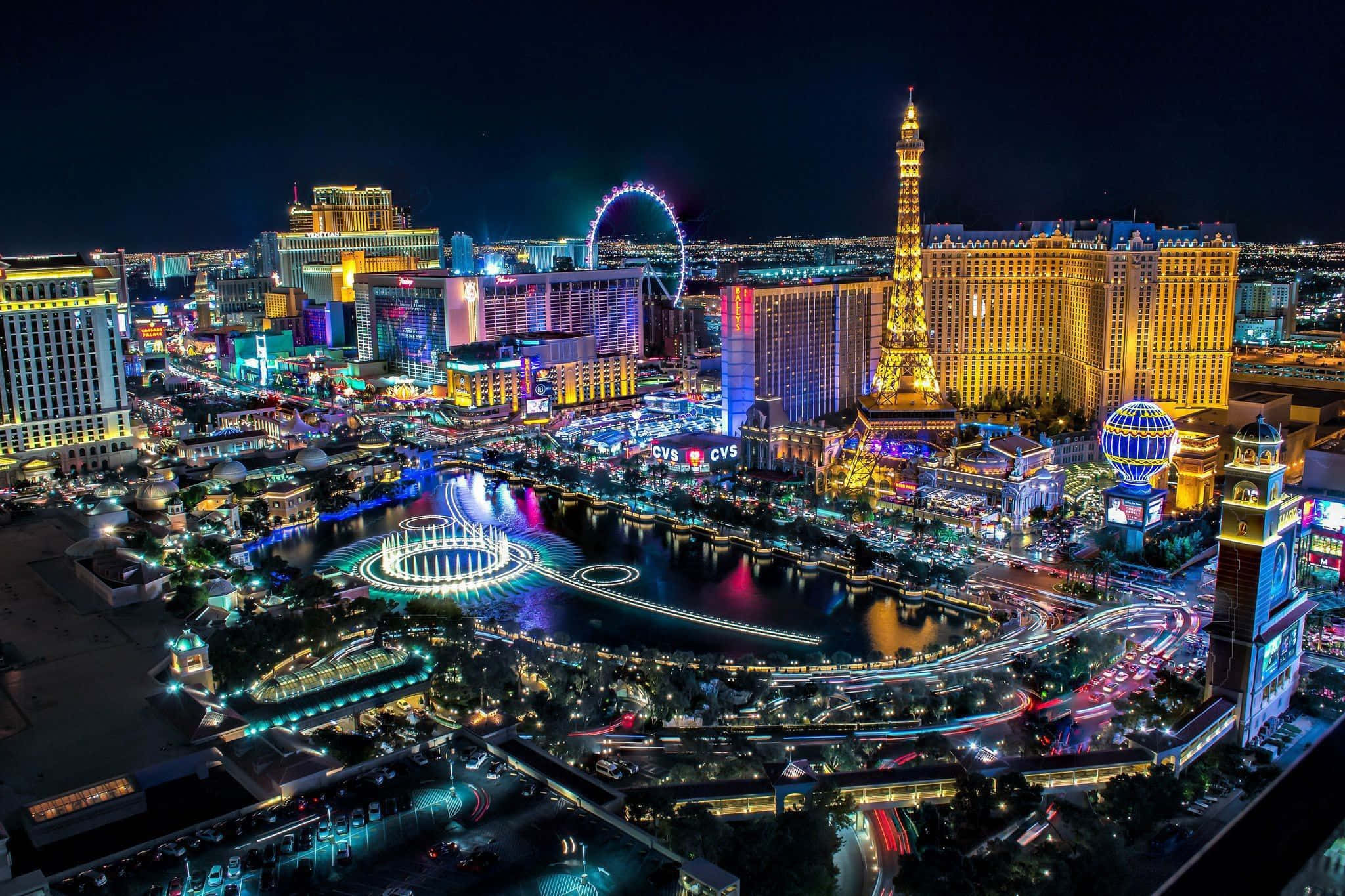 Las Vegas 桌布 壁紙 — 拉斯維加斯令人驚嘆的夜間空中景觀，展示霓虹燈閃爍的酒店、艾菲爾鐵塔複製品和高滾輪摩天輪。