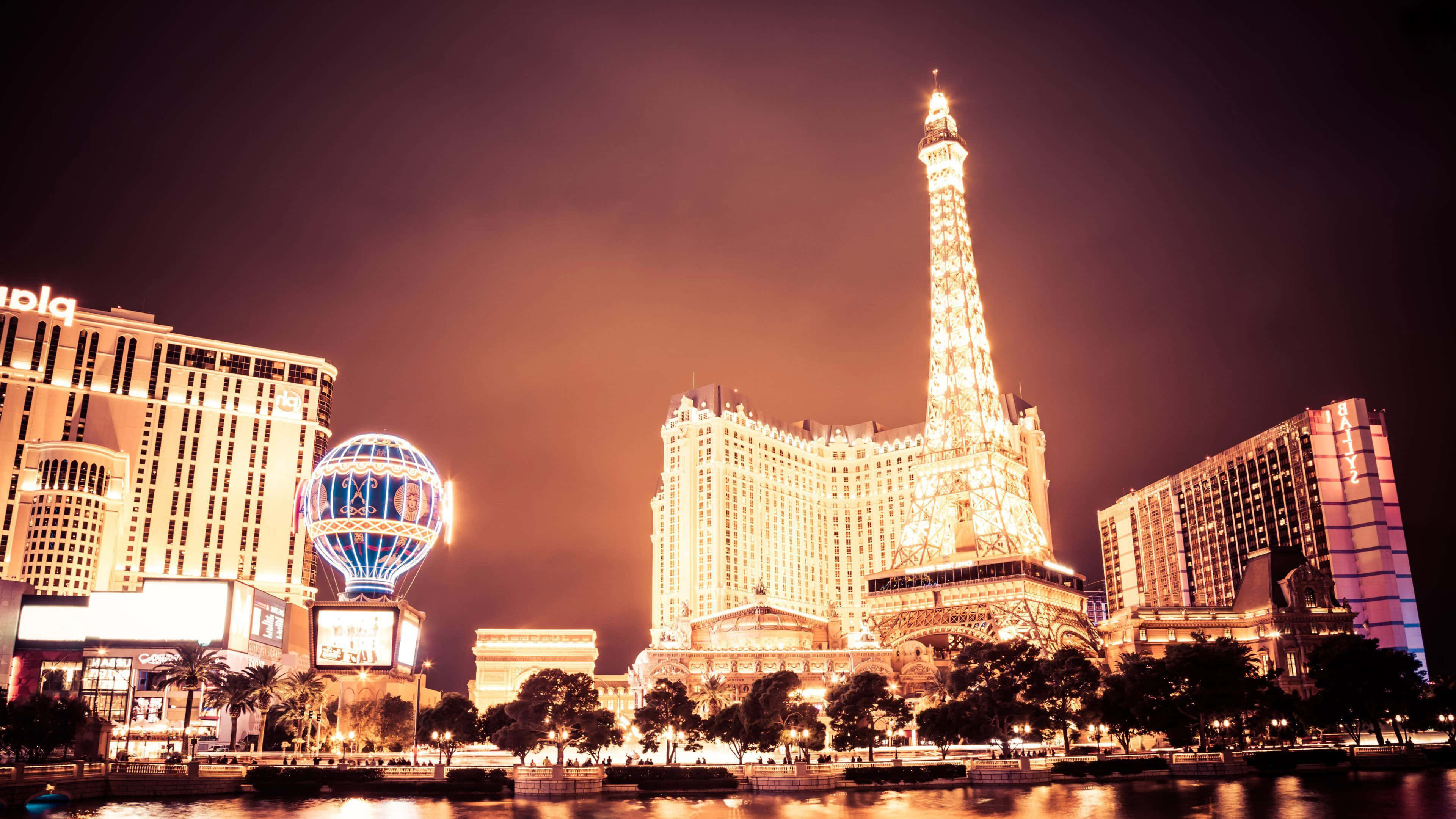 Las Vegas 桌布 壁紙 — 拉斯維加斯大道上耀眼的夜景，展現了亮燈的巴黎拉斯維加斯酒店及其艾菲爾鐵塔複製品和發光的熱氣球。