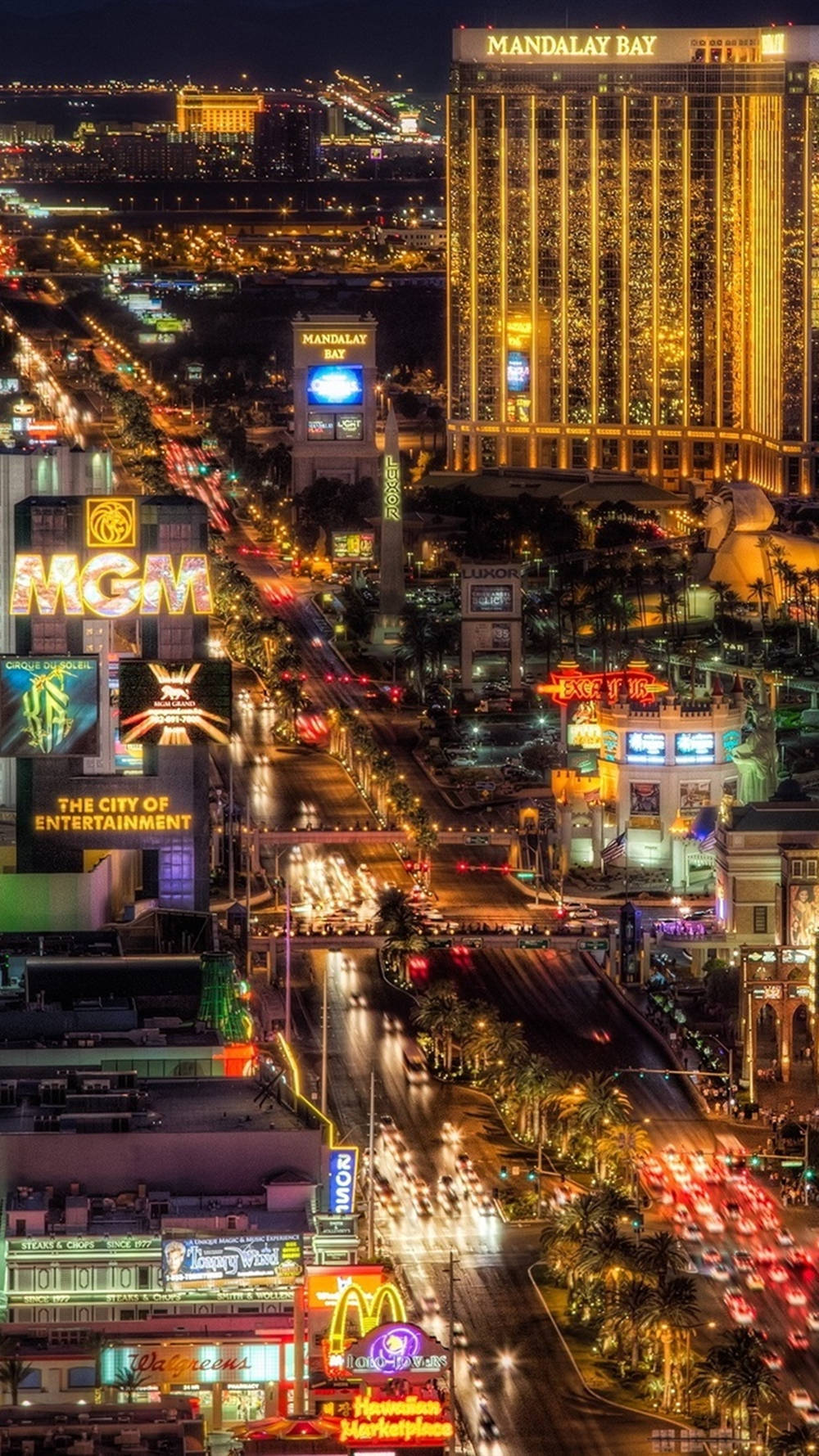 iPhone 桌布 壁紙 — 拉斯維加斯大道令人眼花撩亂的夜間空中景觀，閃爍的賭場招牌和流動的交通燈光。