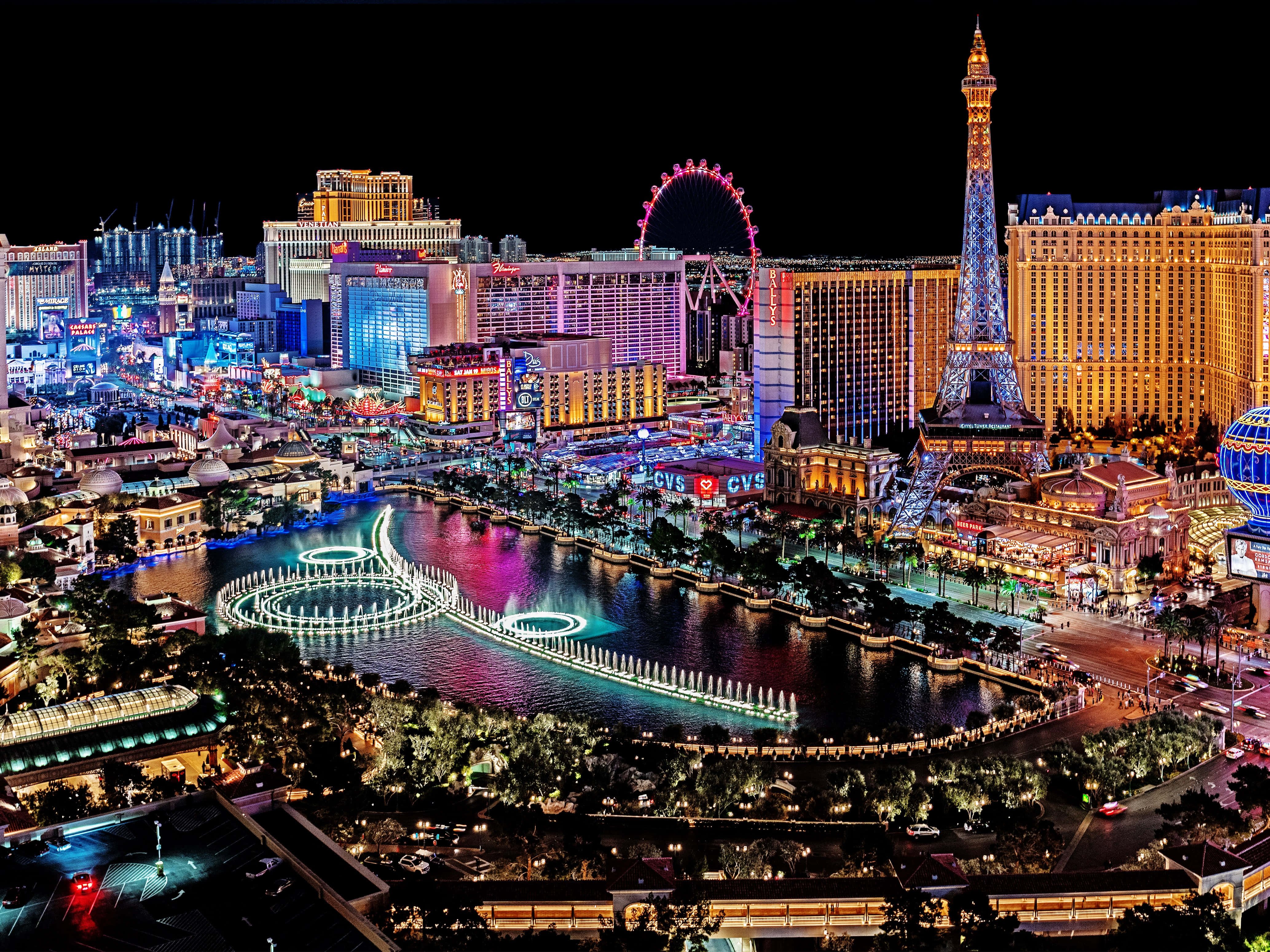 4K Las Vegas 桌布 壁紙 — 拉斯維加斯大道充滿活力的夜景，擁有耀眼的霓虹燈、噴泉以及像艾菲爾鐵塔和豪客摩天輪這樣的標誌性複製品。