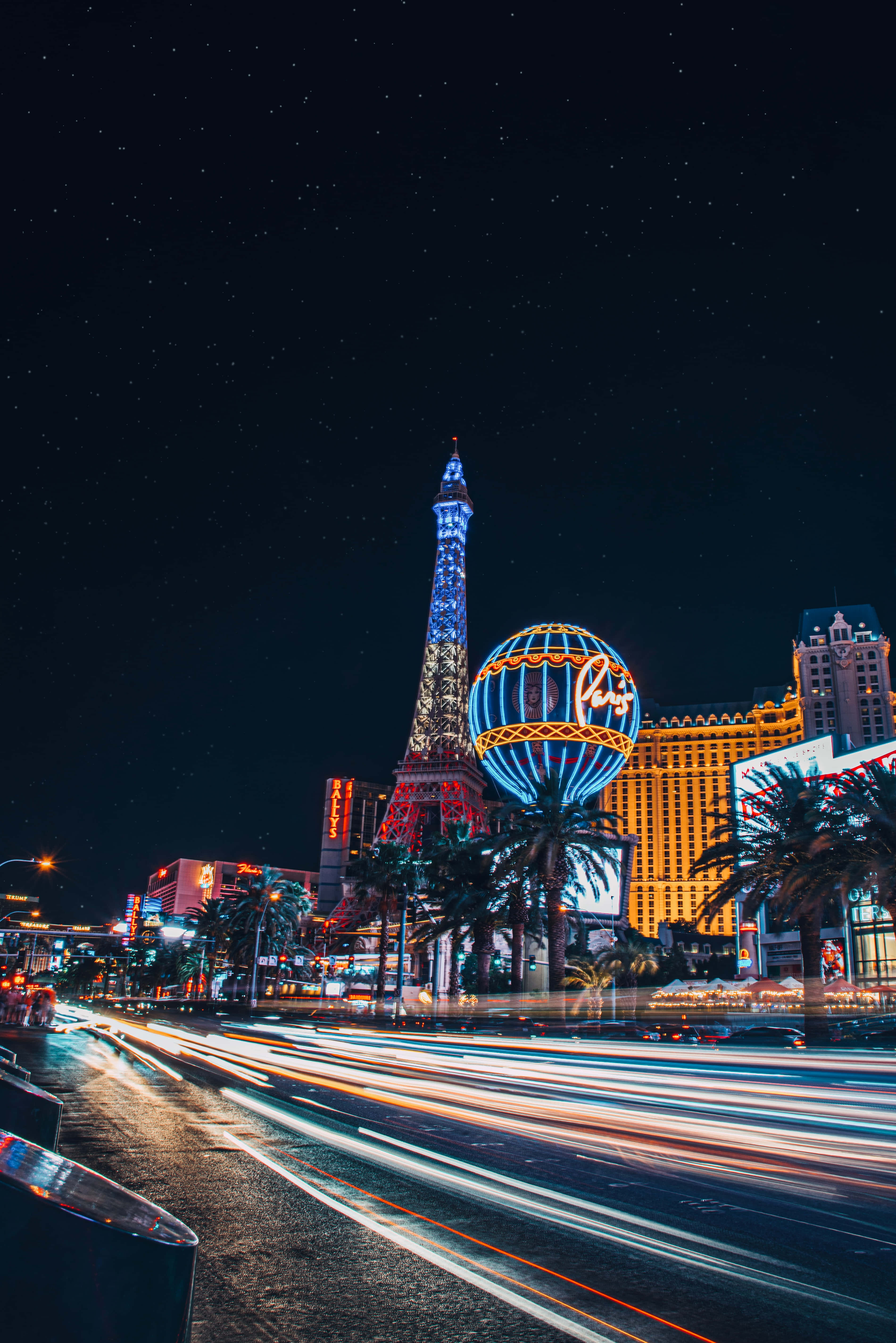 Las Vegas 桌布 壁紙 — 拉斯維加斯大道充滿活力的夜景，有艾菲爾鐵塔複製品和發光的熱氣球，背景是星空。