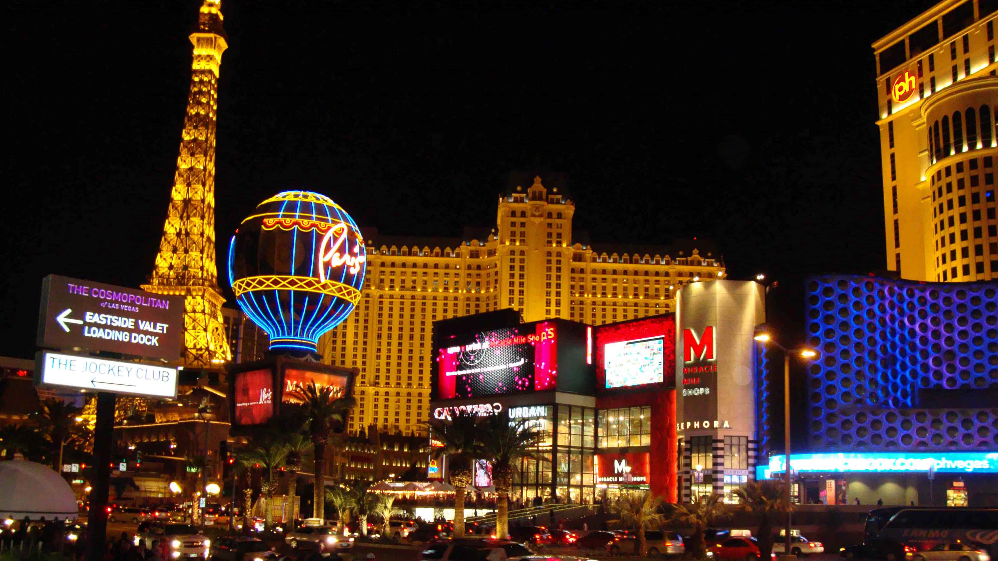 4K Las Vegas 桌布 壁紙 — 拉斯維加斯大道充滿活力的夜景，閃耀的艾菲爾鐵塔複製品熱氣球和令人眼花繚亂的賭場燈光。
