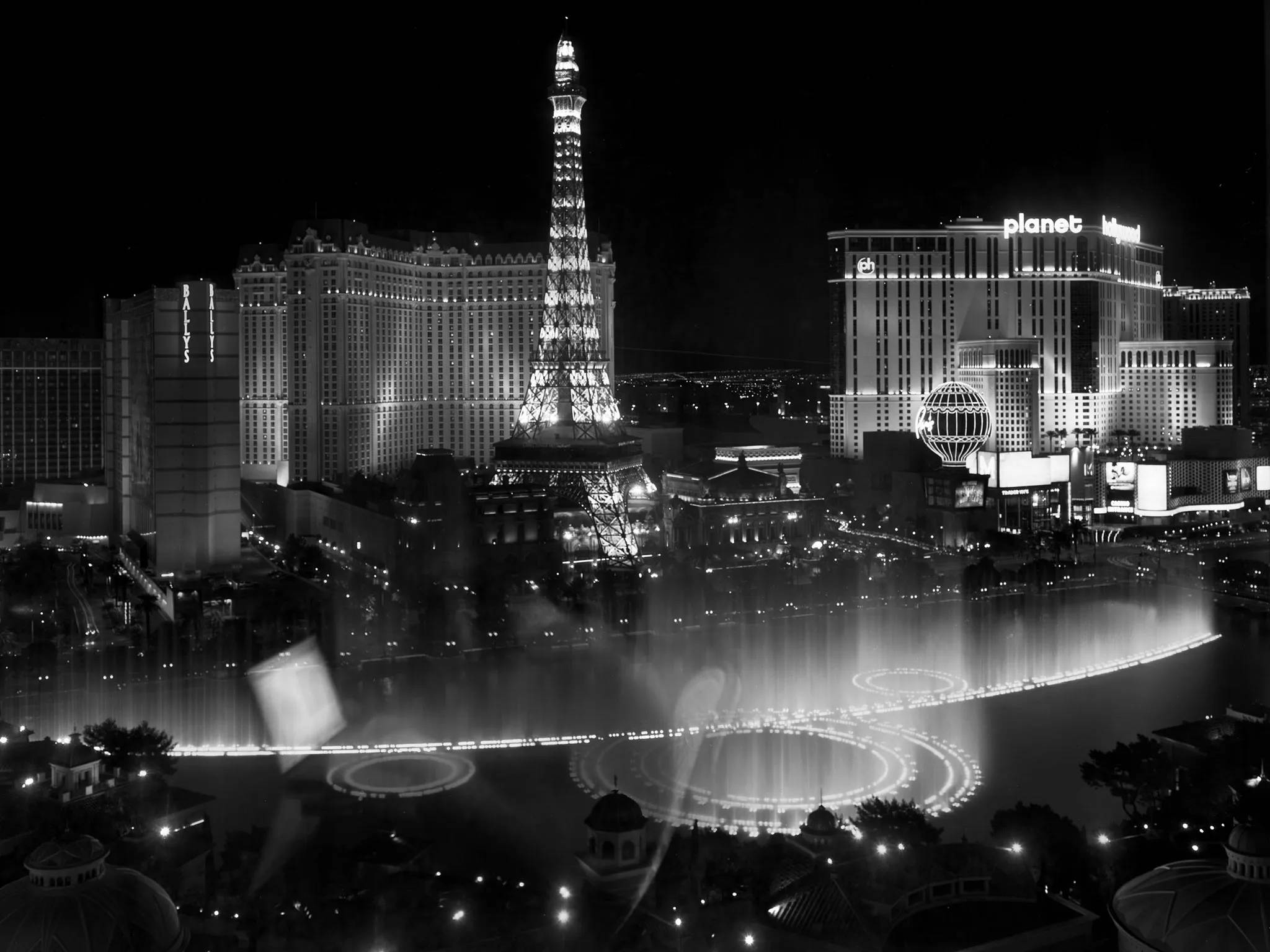 Las Vegas 桌布 壁紙 — 拉斯維加斯大道黑白夜景，展示亮燈的艾菲爾鐵塔複製品和宏偉的噴泉表演。