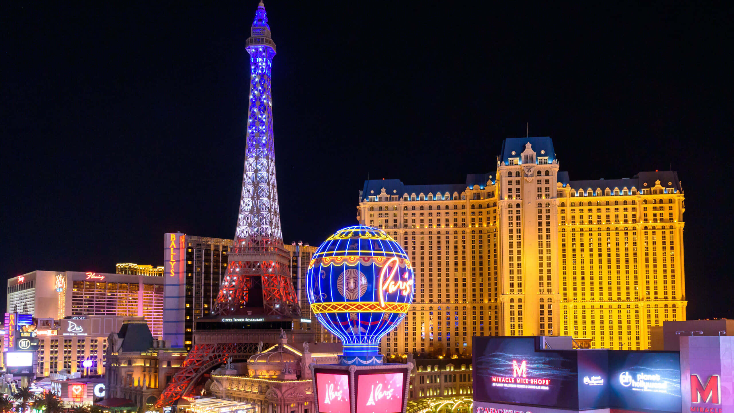 Las Vegas 桌布 壁紙 — 拉斯維加斯璀璨的夜景，以黑暗的天空為背景，閃耀的複製艾菲爾鐵塔和巨大的照明熱氣球。