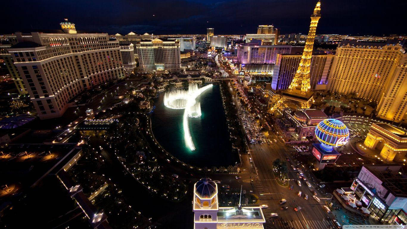 Las Vegas 桌布 壁紙 — 拉斯維加斯的夜間空中景觀，展示貝拉吉奧噴泉和艾菲爾鐵塔複製品在城市燈光下閃耀。