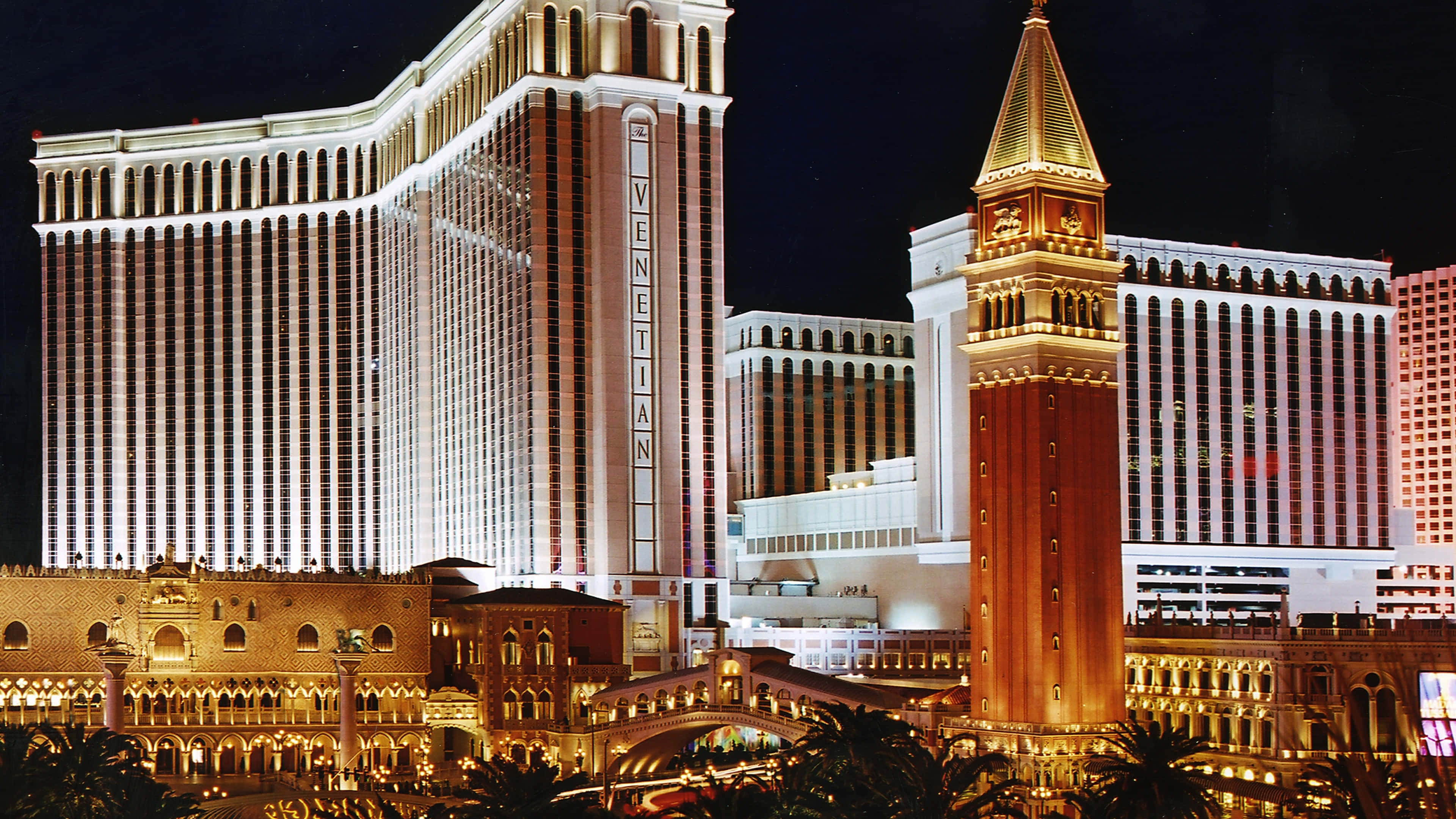 4K Las Vegas 桌布 壁紙 — 拉斯維加斯的威尼斯人酒店在夜晚閃耀，金色燈光照亮其宏偉建築和複製橋樑。
