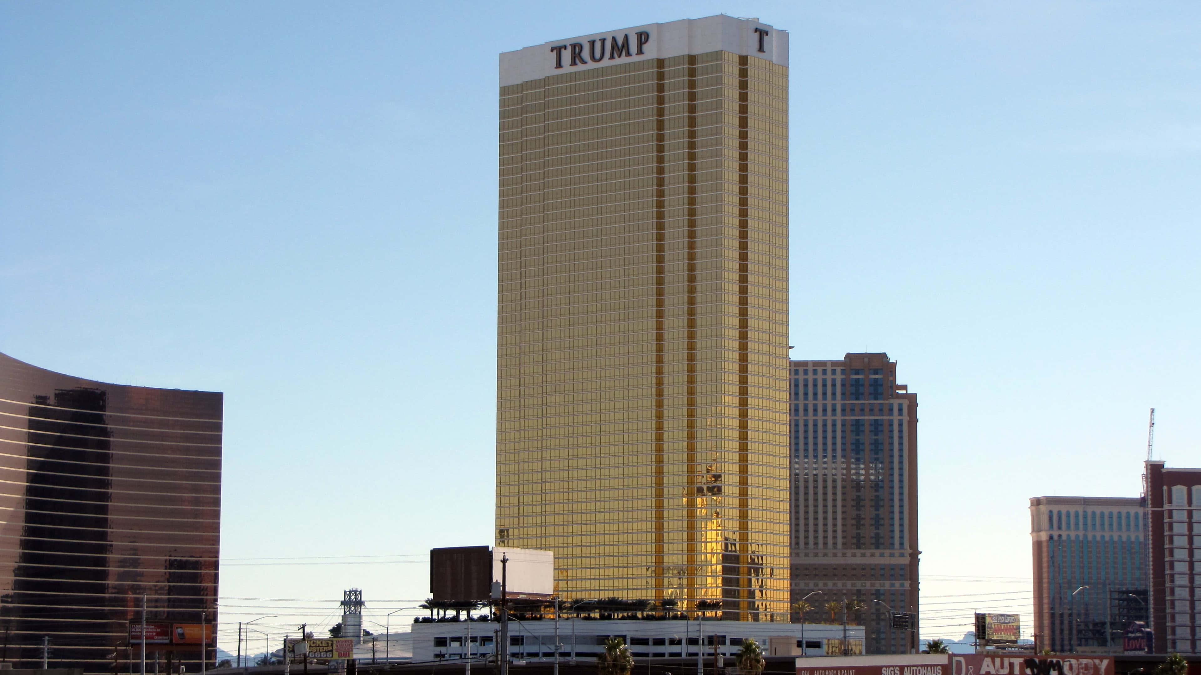 4K Las Vegas 桌布 壁紙 — 拉斯維加斯的金色特朗普大廈在晴朗的藍天下閃耀，周圍環繞著現代建築。