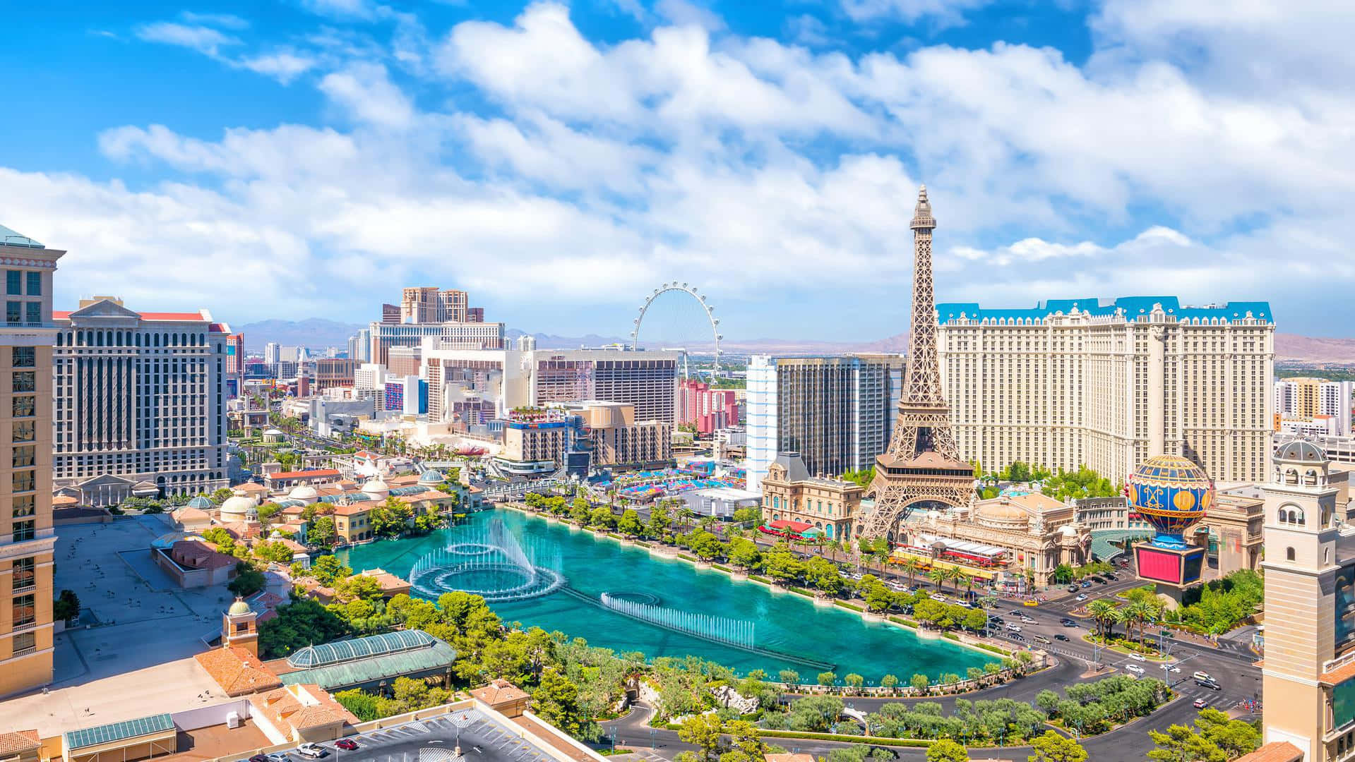 Nevada 桌布 壁紙 — 拉斯維加斯的鳥瞰圖，展示了在明亮藍天和蓬鬆雲朵下的艾菲爾鐵塔複製品和充滿活力的噴泉。