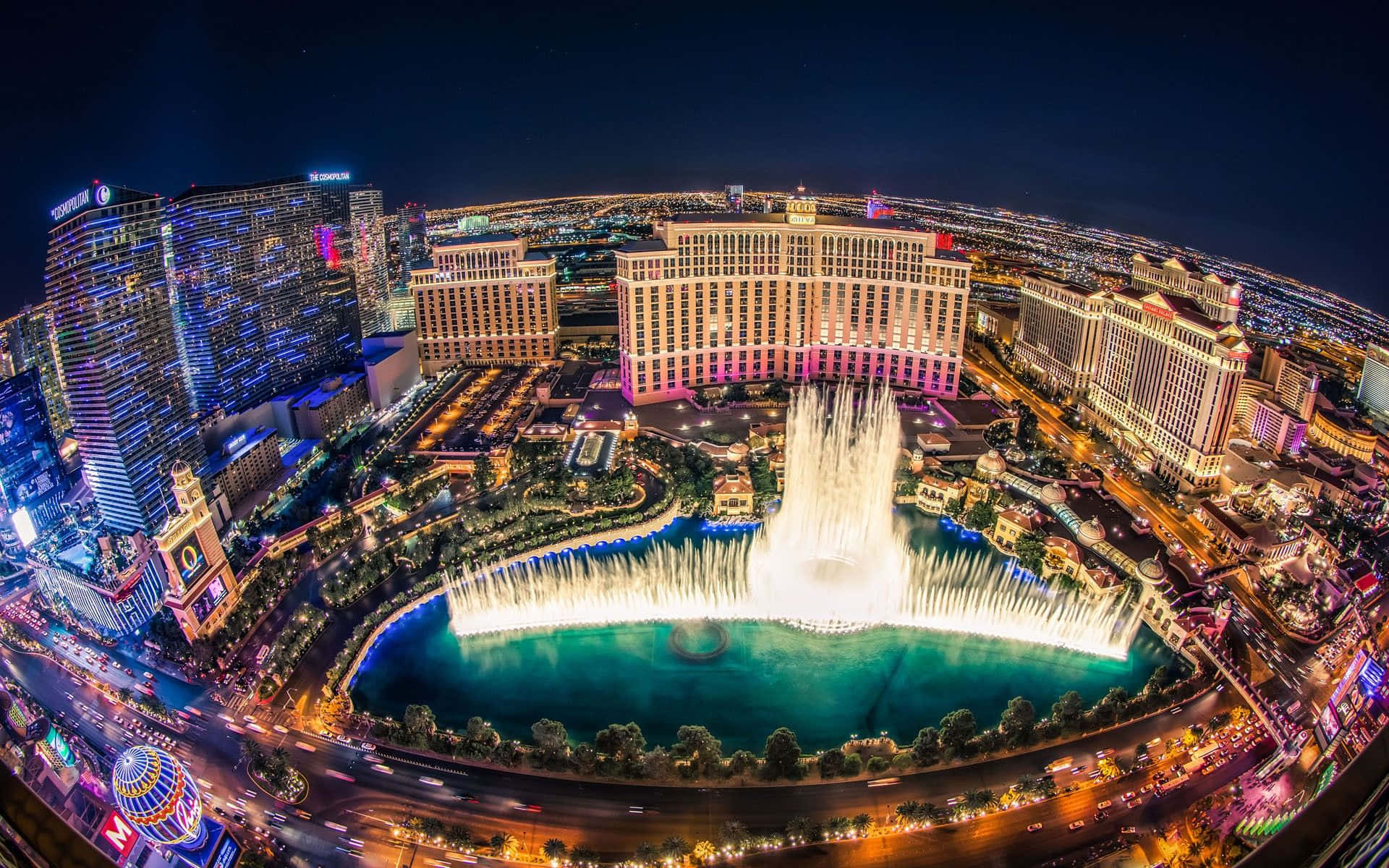 Las Vegas Skyline 桌布 壁紙 — 拉斯維加斯貝拉吉奧噴泉的迷人夜間鳥瞰圖，充滿活力的城市燈光和車流軌跡。