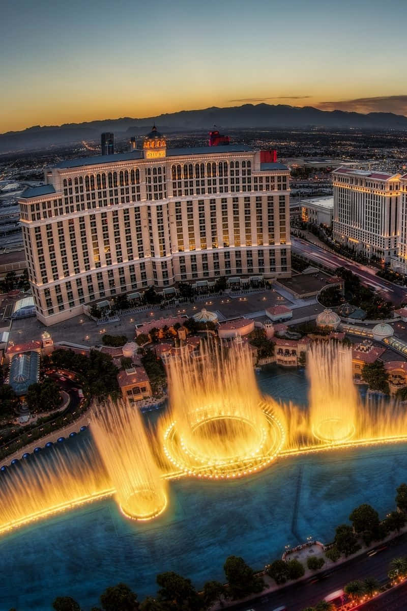 Nevada 桌布 壁紙 — 拉斯維加斯貝拉吉奧酒店在黃昏時的鳥瞰圖，其標誌性的金色噴泉在燈火通明的建築前舞動。