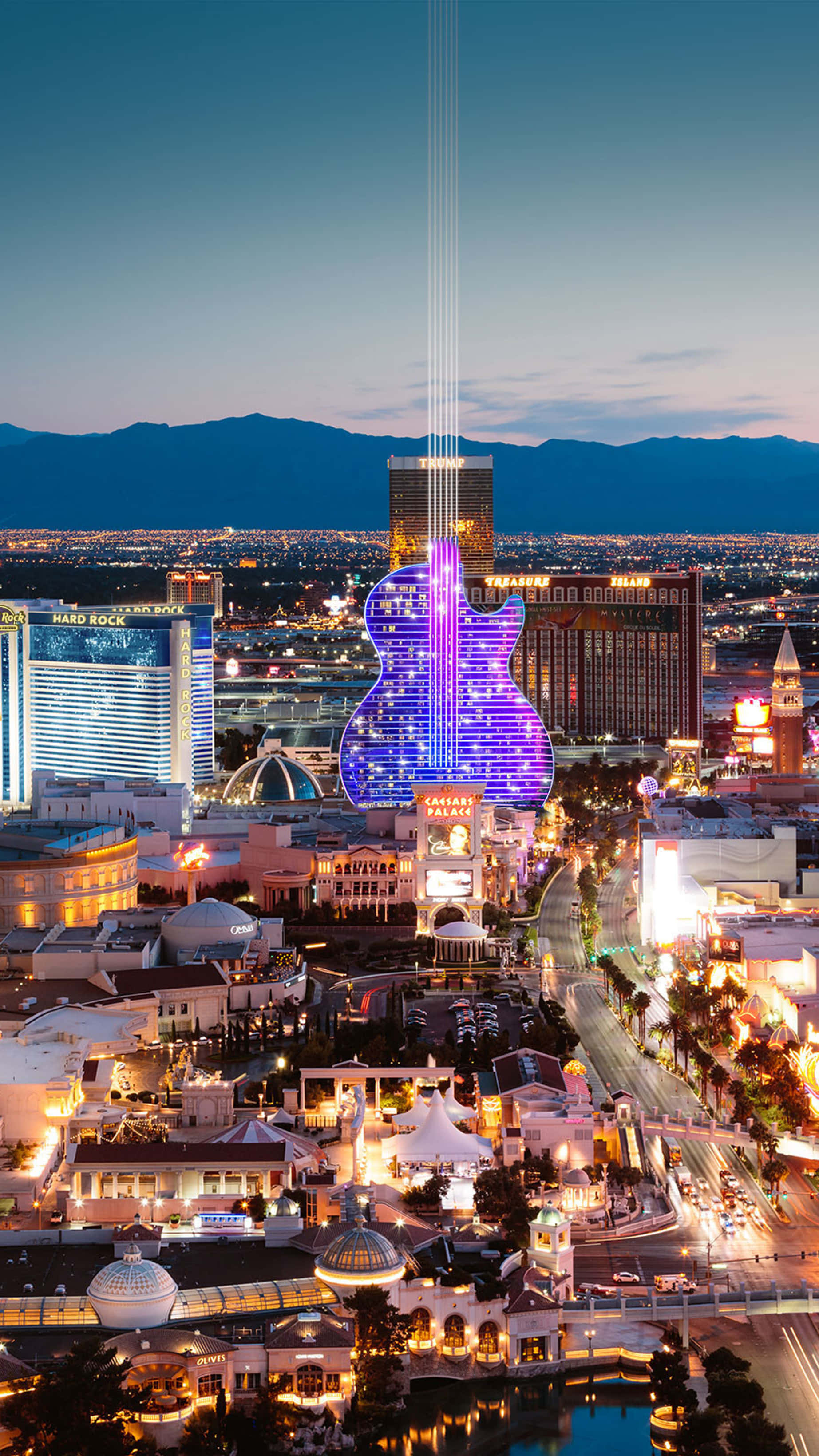Las Vegas 桌布 壁紙 — 拉斯維加斯迷人的黃昏景色，展示了標誌性的結他形凱撒皇宮，配以充滿活力的紫色燈光和周圍燈火通明的酒店。