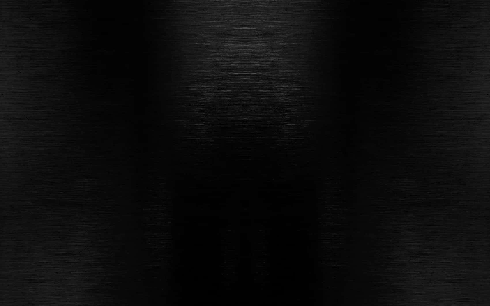 Glossy Black 桌布 壁紙 — 拉絲黑色金屬表面的特寫，帶有微妙的水平紋理和漸變照明。