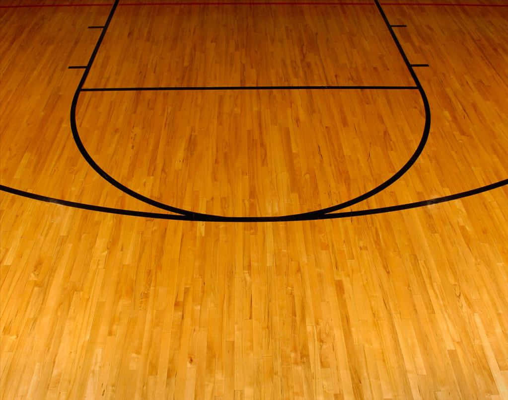 Basketball Court 桌布 壁紙 — 拋光木質籃球場地板，在明亮燈光下呈現大膽的黑色線條和溫暖的琥珀色調。