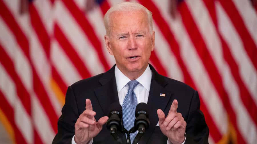 USA Flag 桌布 壁紙 — 拜登總統在講台上發言，身後有美國國旗，雙手做手勢。