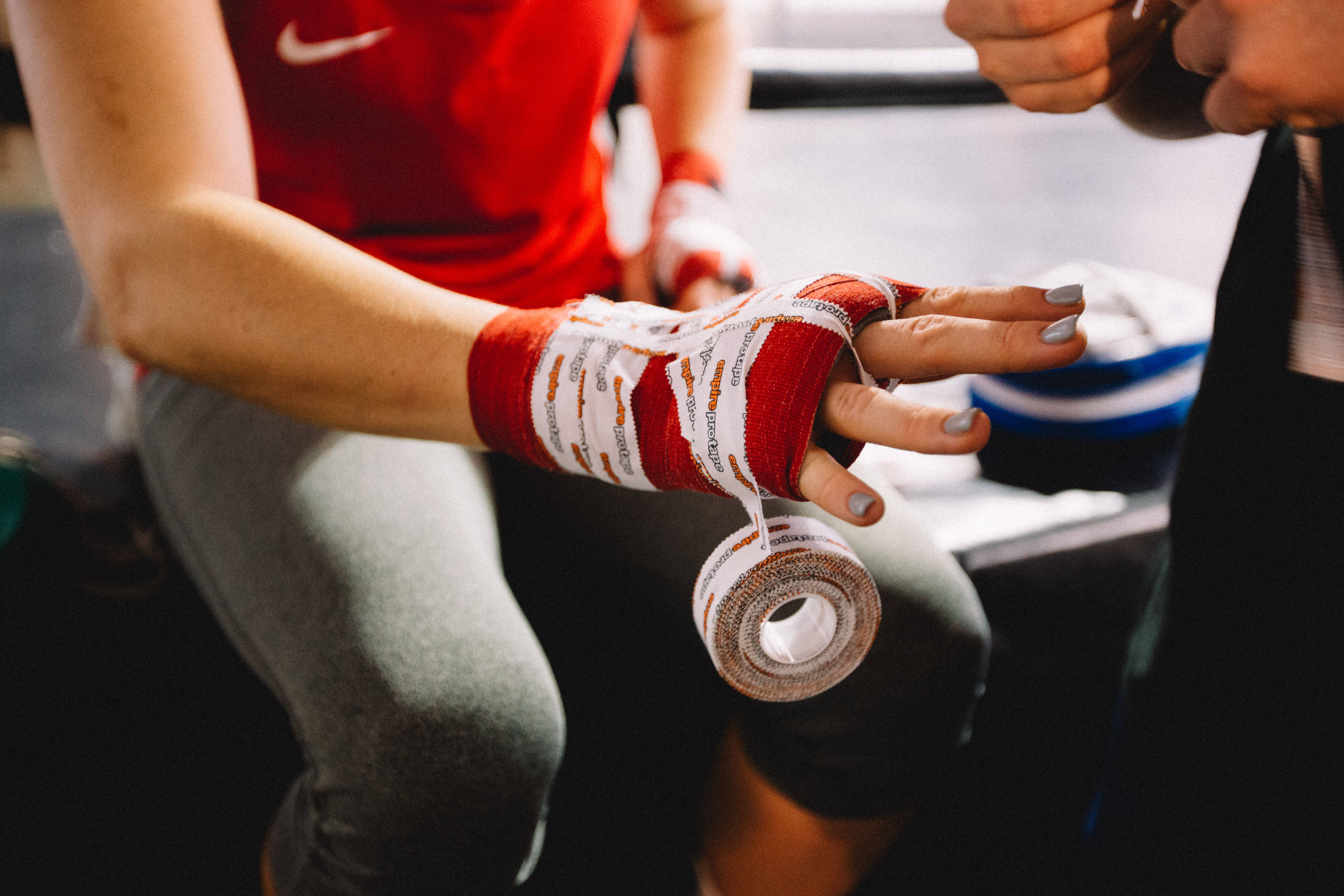 UFC 桌布 壁紙 — 拳手的手在健身房被教練用紅白拳擊繃帶包裹的特寫。