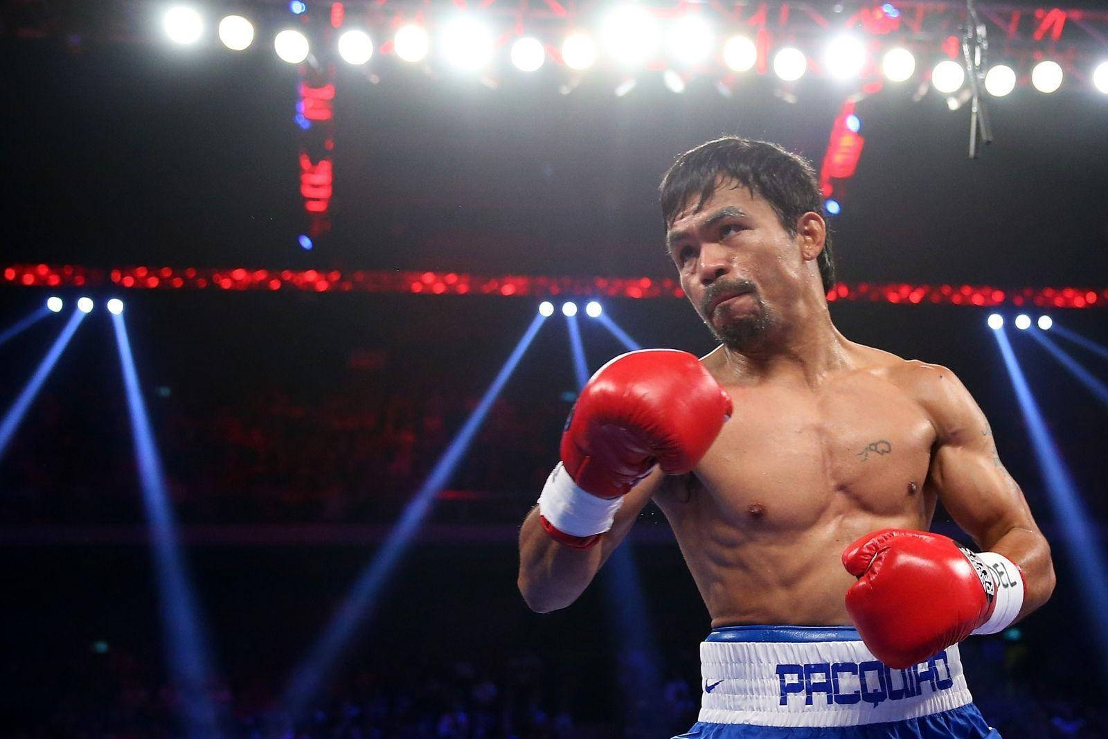 Boxing 桌布 壁紙 — 拳擊手曼尼·帕奎奧在明亮燈光下站在擂台上，戴著紅色手套和藍色短褲。