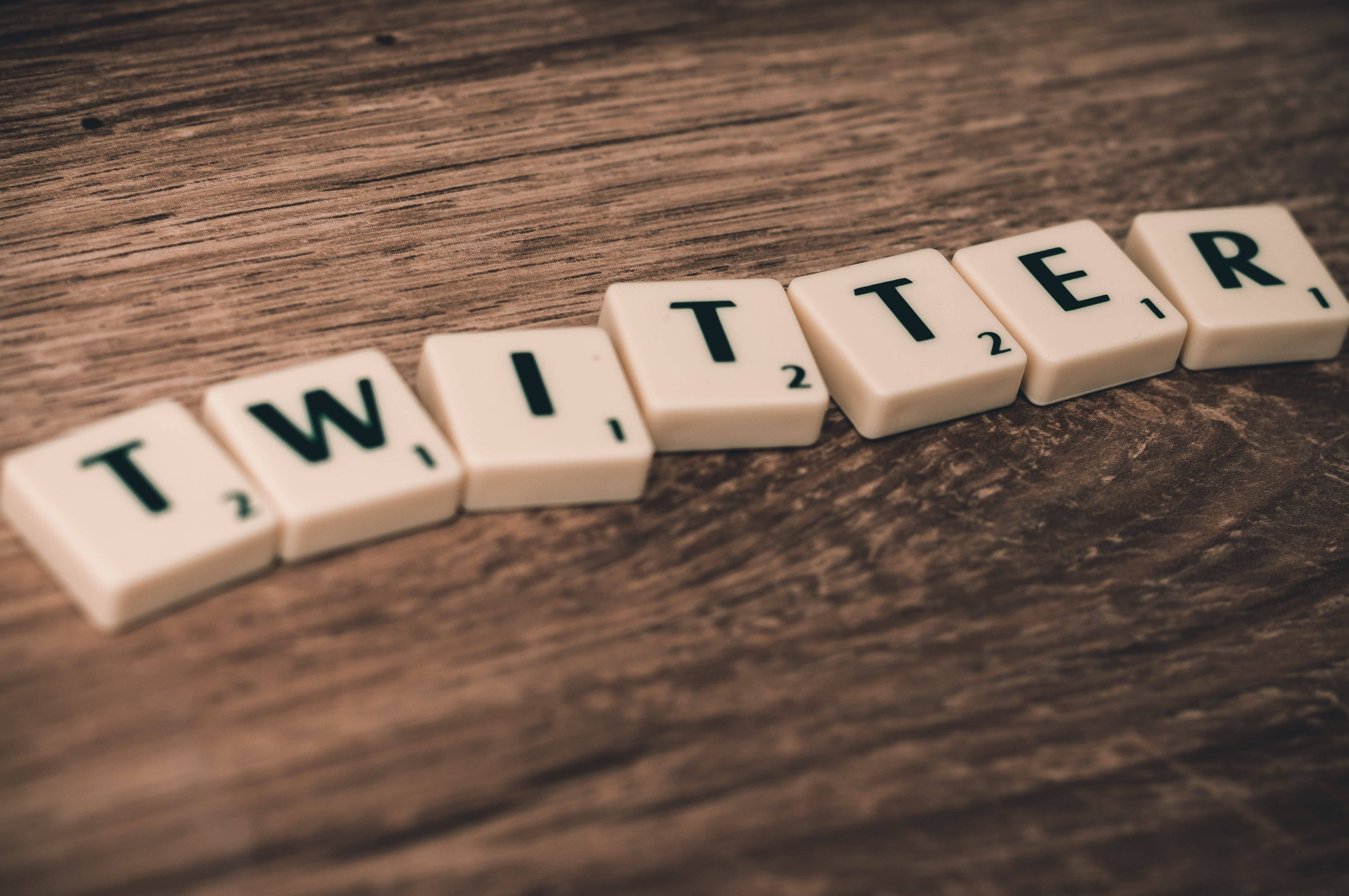 Twitter 桌布 壁紙 — 拼出 twitter 的 Scrabble 字母牌放在有紋理的木質表面上，景深較淺。
