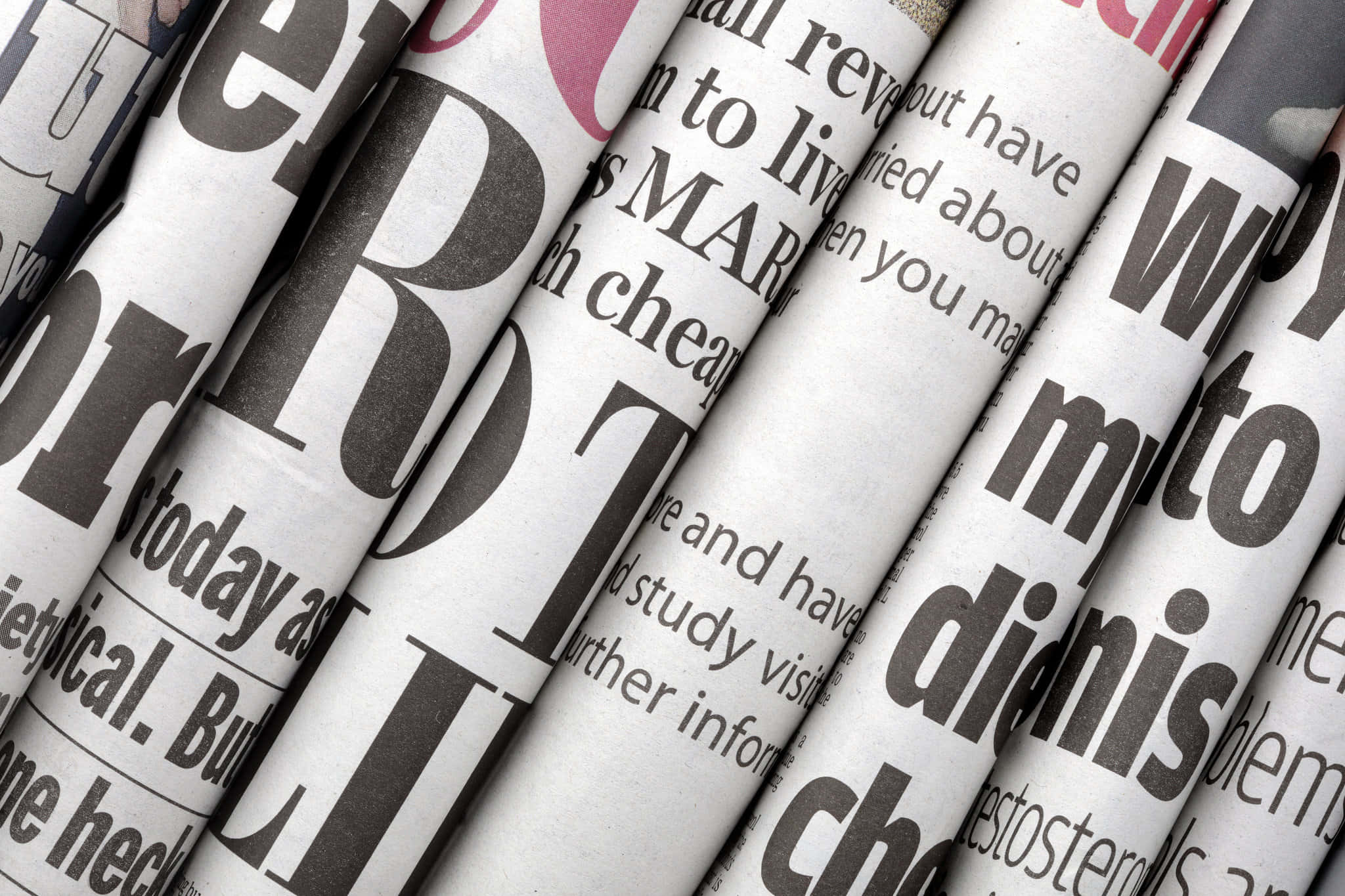 Newspaper 桌布 壁紙 — 捲起報紙部分的特寫，揭示粗體標題和密集文字呈對角線圖案。