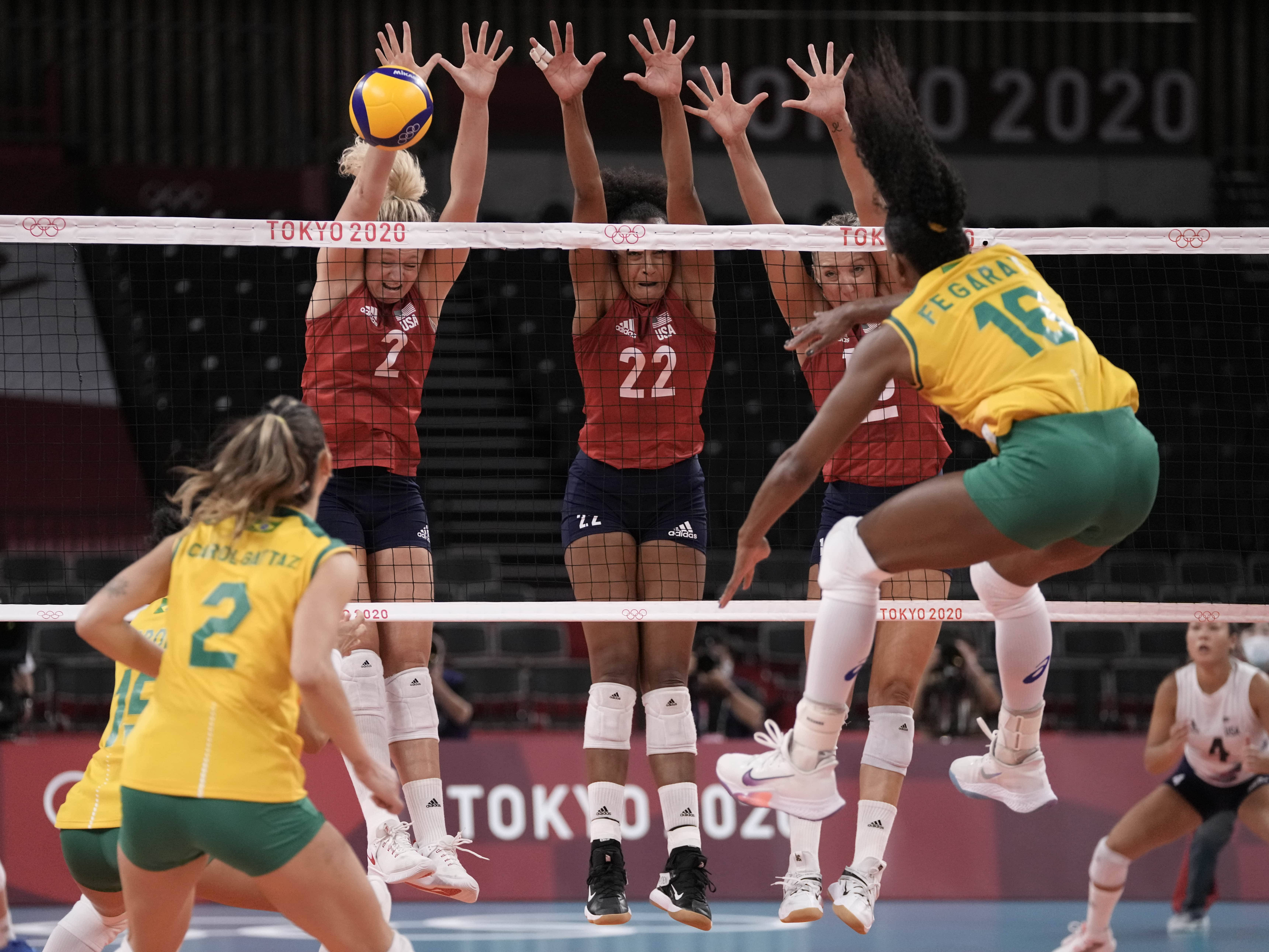 Volleyball 桌布 壁紙 — 排球運動員在激烈的奧運比賽中跳起並伸手觸網，球懸浮在上方。