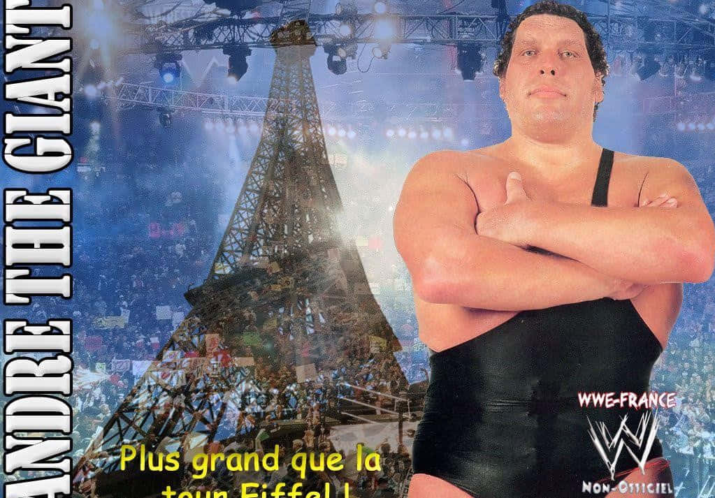 french 桌布 壁紙 — 摔角手 Andre the Giant 自信地交叉雙臂，站在擠滿人群的艾菲爾鐵塔競技場前，舞台燈光璀璨。