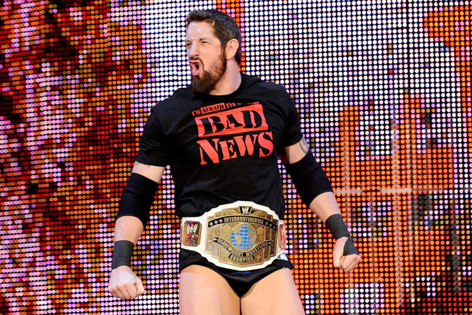 Champion 桌布 壁紙 — 摔角手 Bad News Barrett 身穿黑色T恤和冠軍腰帶，在充滿活力的像素化背景下勝利咆哮。