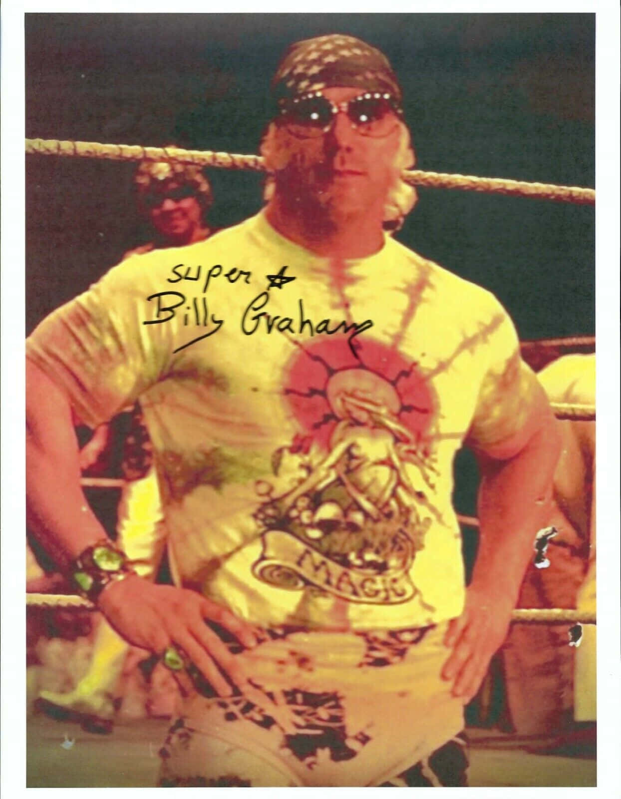 WWE 桌布 壁紙 — 摔角手 Billy Graham 自信地站在擂台上，身穿帶有太陽圖案的黃色紮染襯衫和太陽眼鏡。