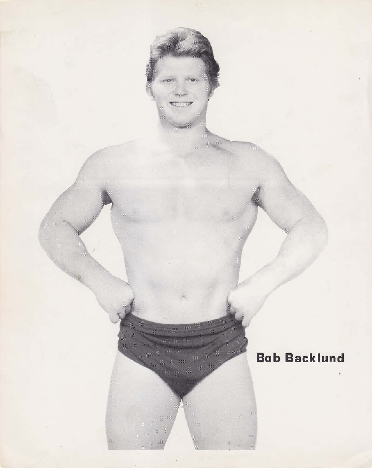 摔角 桌布 壁紙 — 摔角手 Bob Backlund 穿著短褲，雙手叉腰自信擺姿勢的黑白肖像。