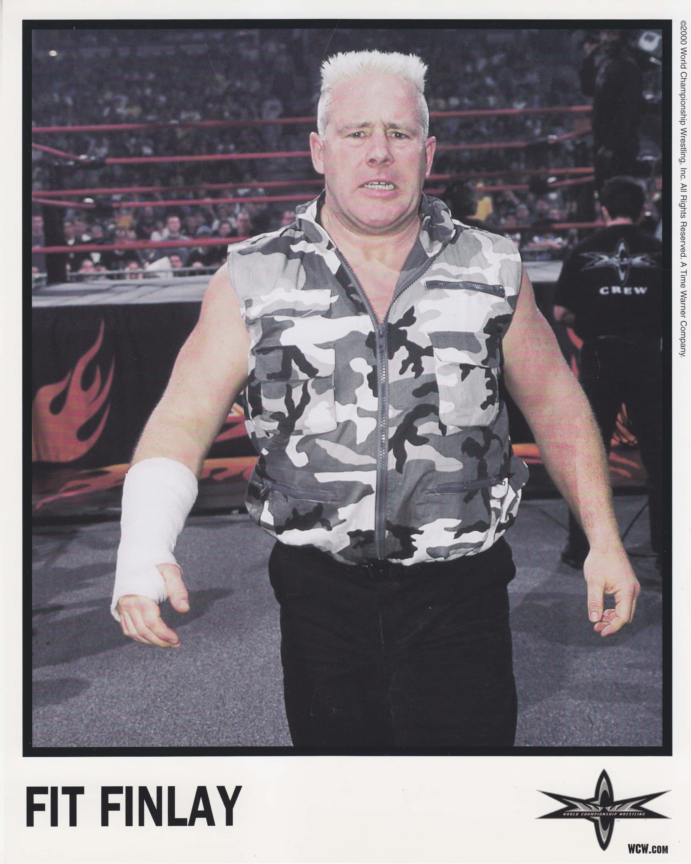 WWE 桌布 壁紙 — 摔角手 Fit Finlay 身穿迷彩背心及白色手腕繃帶，站在擂台上，背後有群眾。