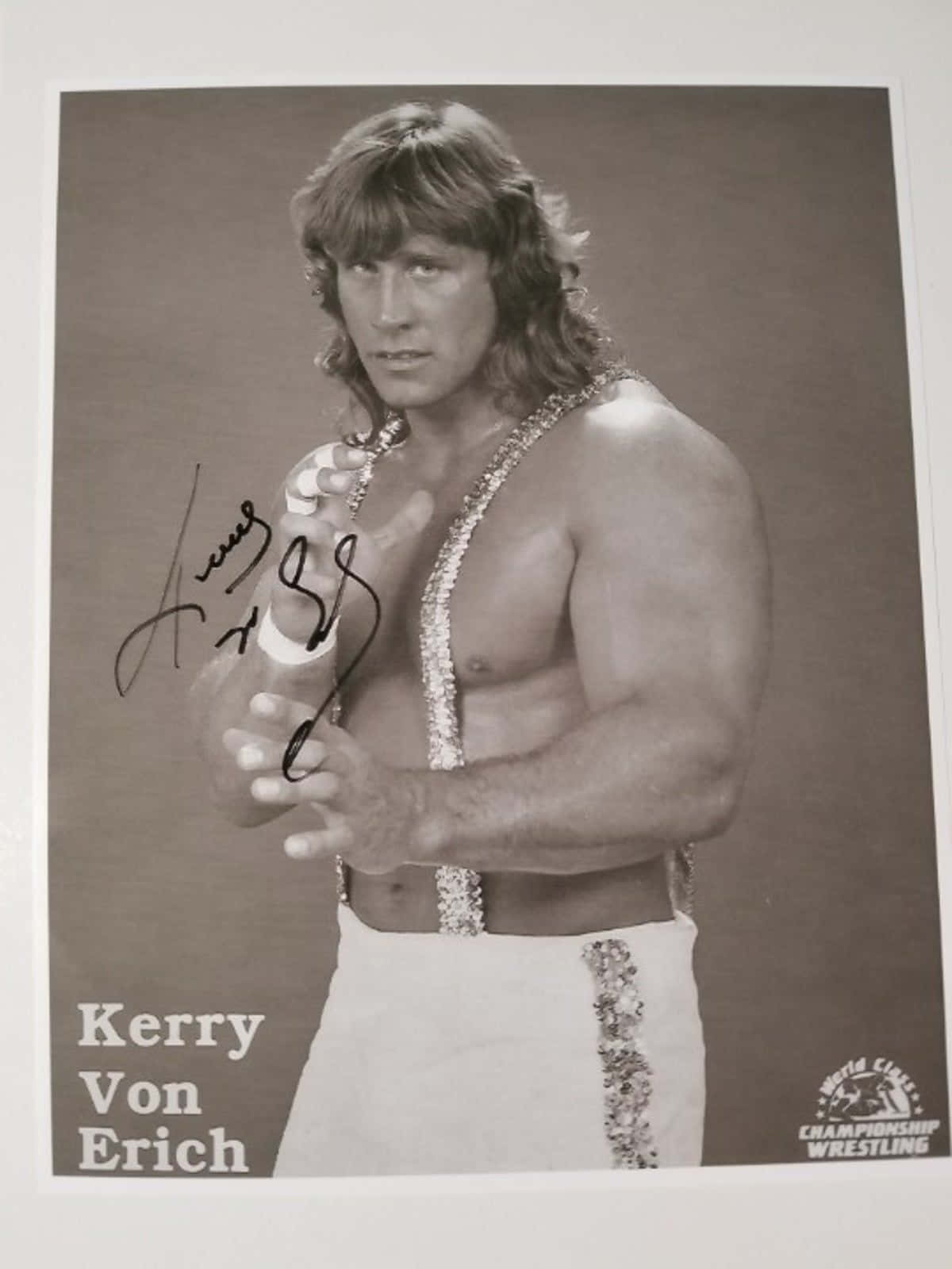 人像動態 桌布 壁紙 — 摔角手 Kerry Von Erich 的黑白工作室肖像，身穿閃亮摔角服，附有簽名和名牌。