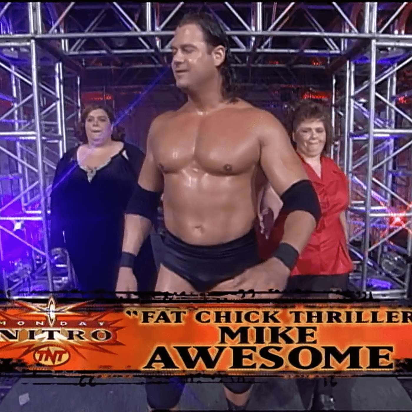 摔角 桌布 壁紙 — 摔角手 Mike Awesome 赤裸上身站在擂台上，身後有兩名女子，在明亮的舞台燈光下。