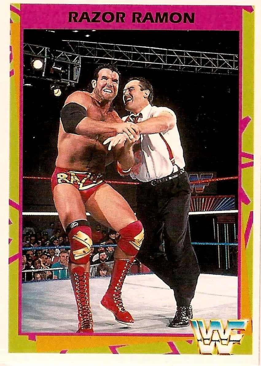 WWE 桌布 壁紙 — 摔角手 Razor Ramon 身穿紅色裝備，在明亮的場館燈光下於 WWE 擂台上與裁判糾纏。