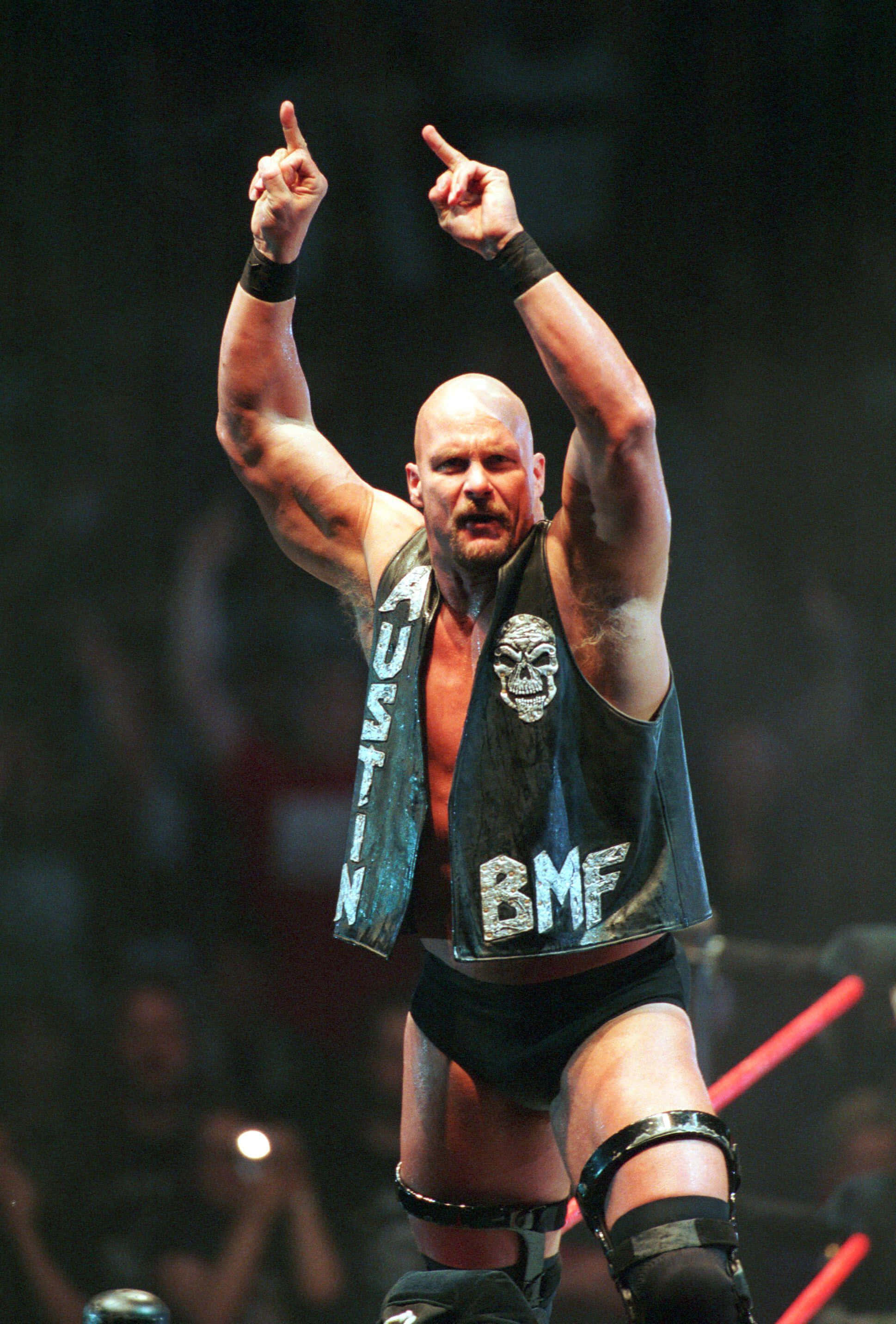 WWE 桌布 壁紙 — 摔角手 Stone Cold Steve Austin 身穿印有骷髏頭和 BMF 字樣的黑色背心，在燈光璀璨的擂台上勝利地舉起雙食指。