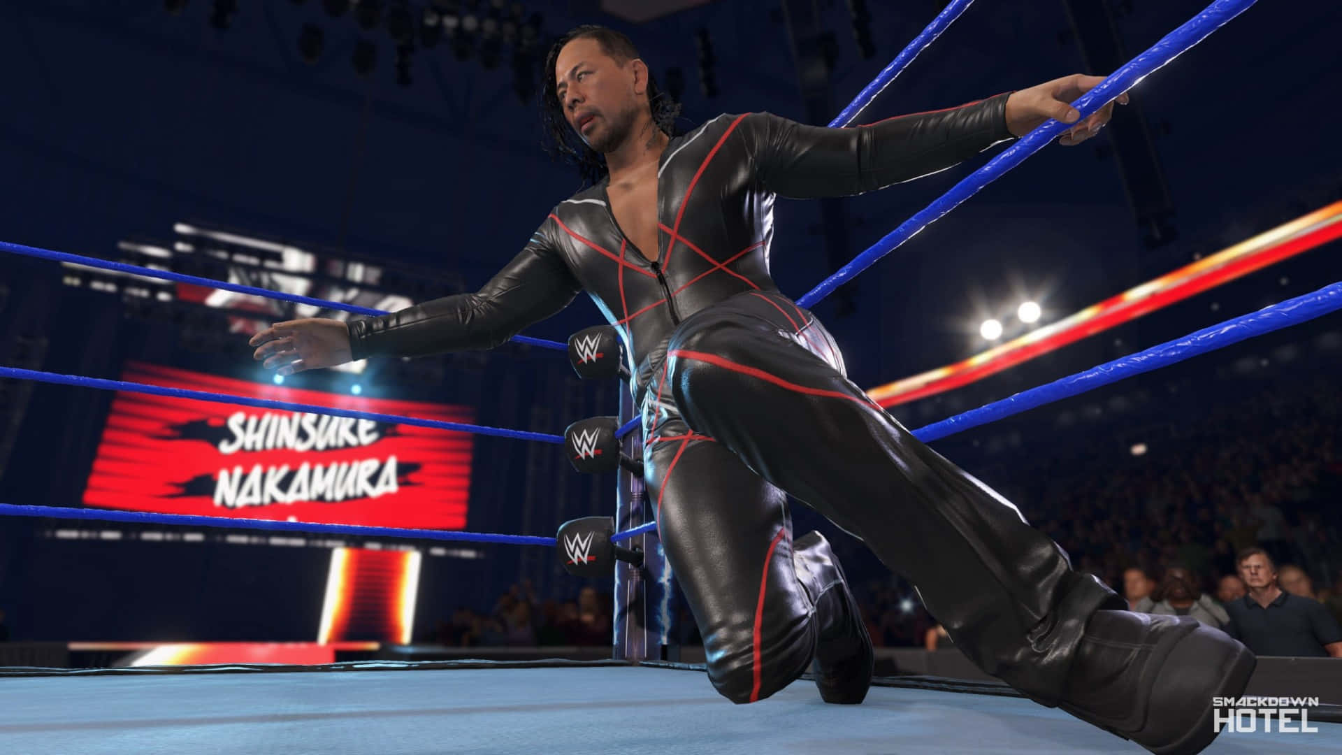 WWE 桌布 壁紙 — 摔角手中邑真輔穿著黑色和紅色皮革裝備，在燈光明亮的摔角場中蹲下。