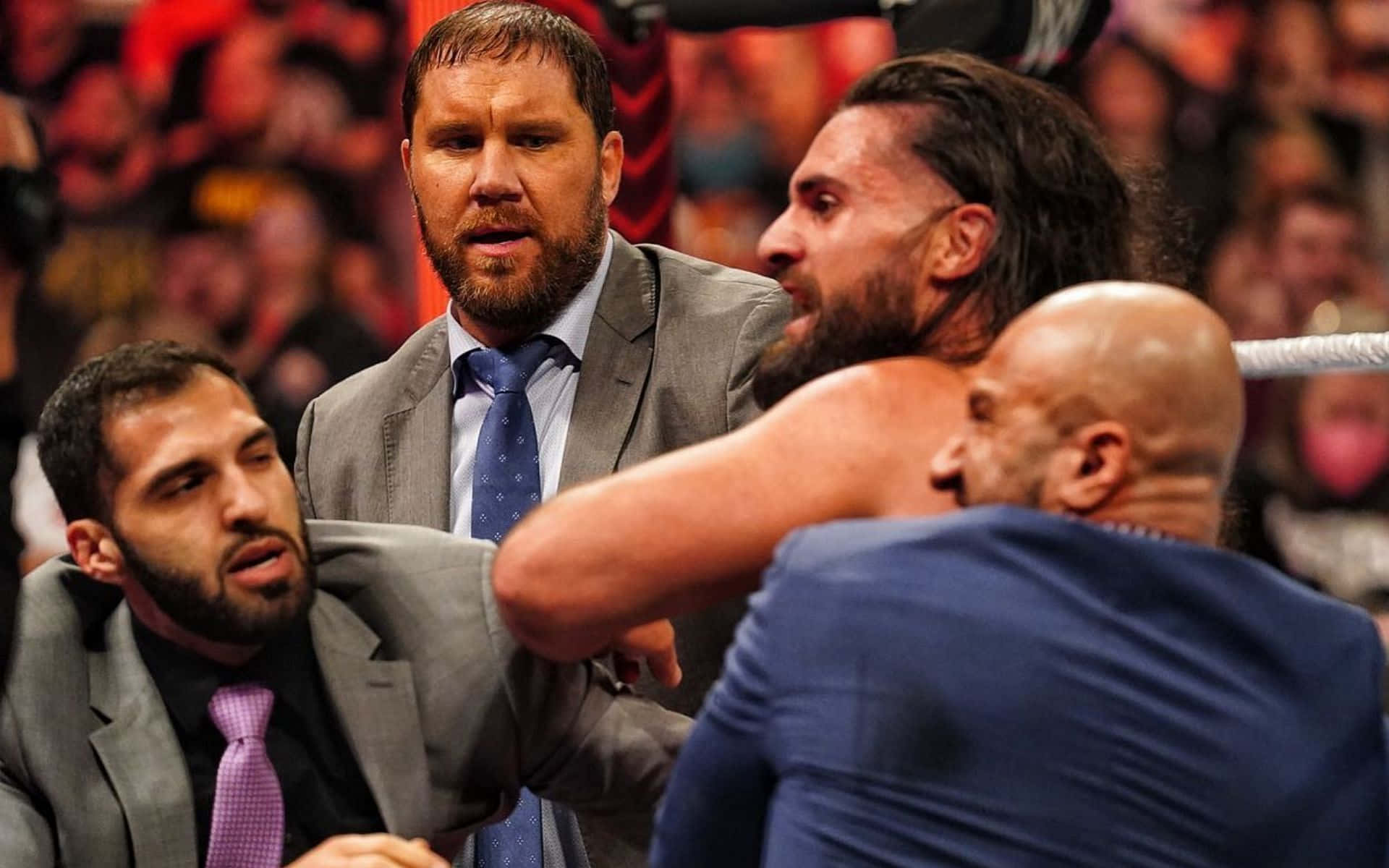 WWE 桌布 壁紙 — 摔角手和經理人在擠滿觀眾的擂台上激烈衝突，場館燈光明亮，粉絲們大聲呼喊。