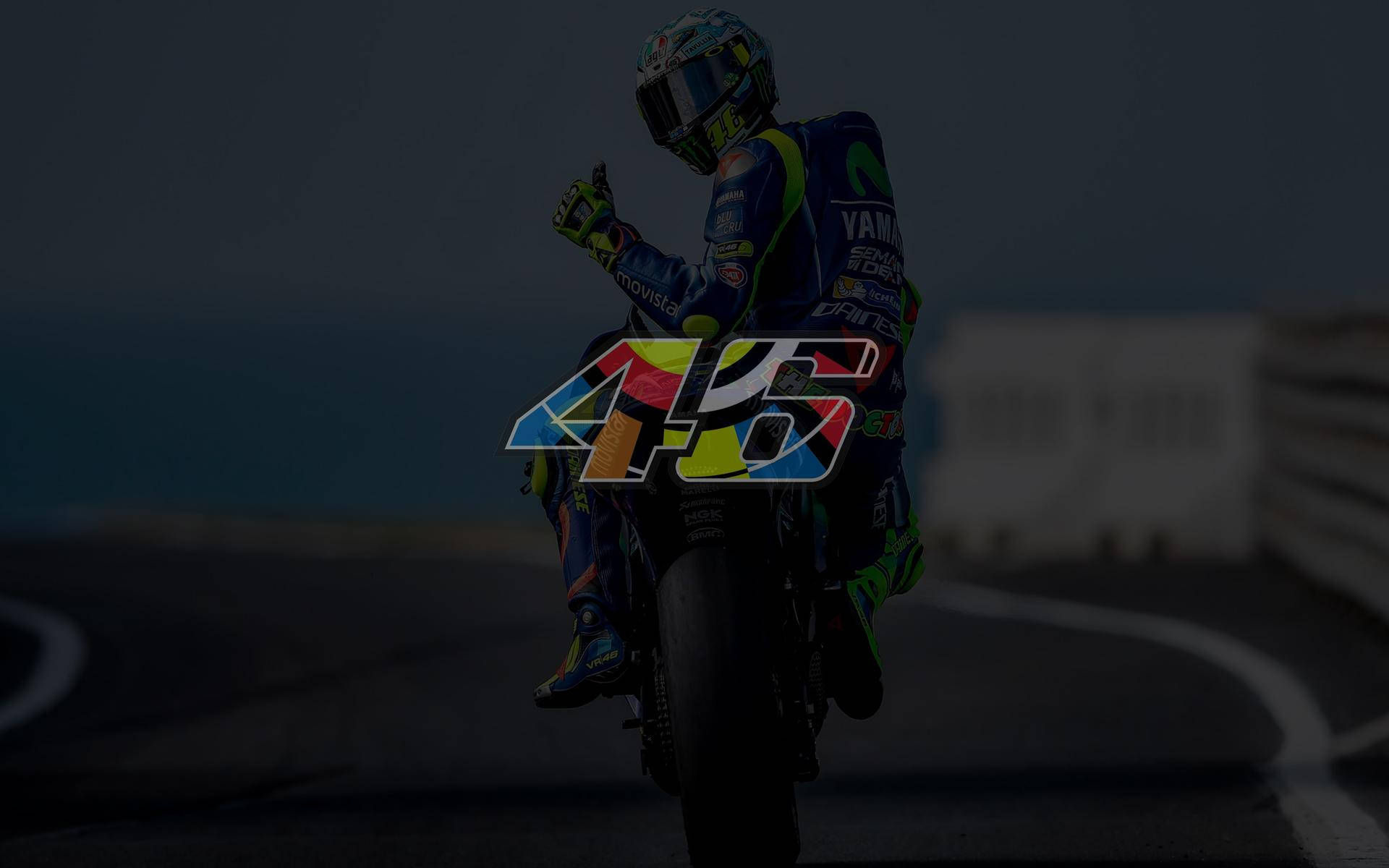 Racing 桌布 壁紙 — 摩托車手穿著賽車裝備在賽道上慶祝，並帶有大型彩色46號標誌覆蓋層。