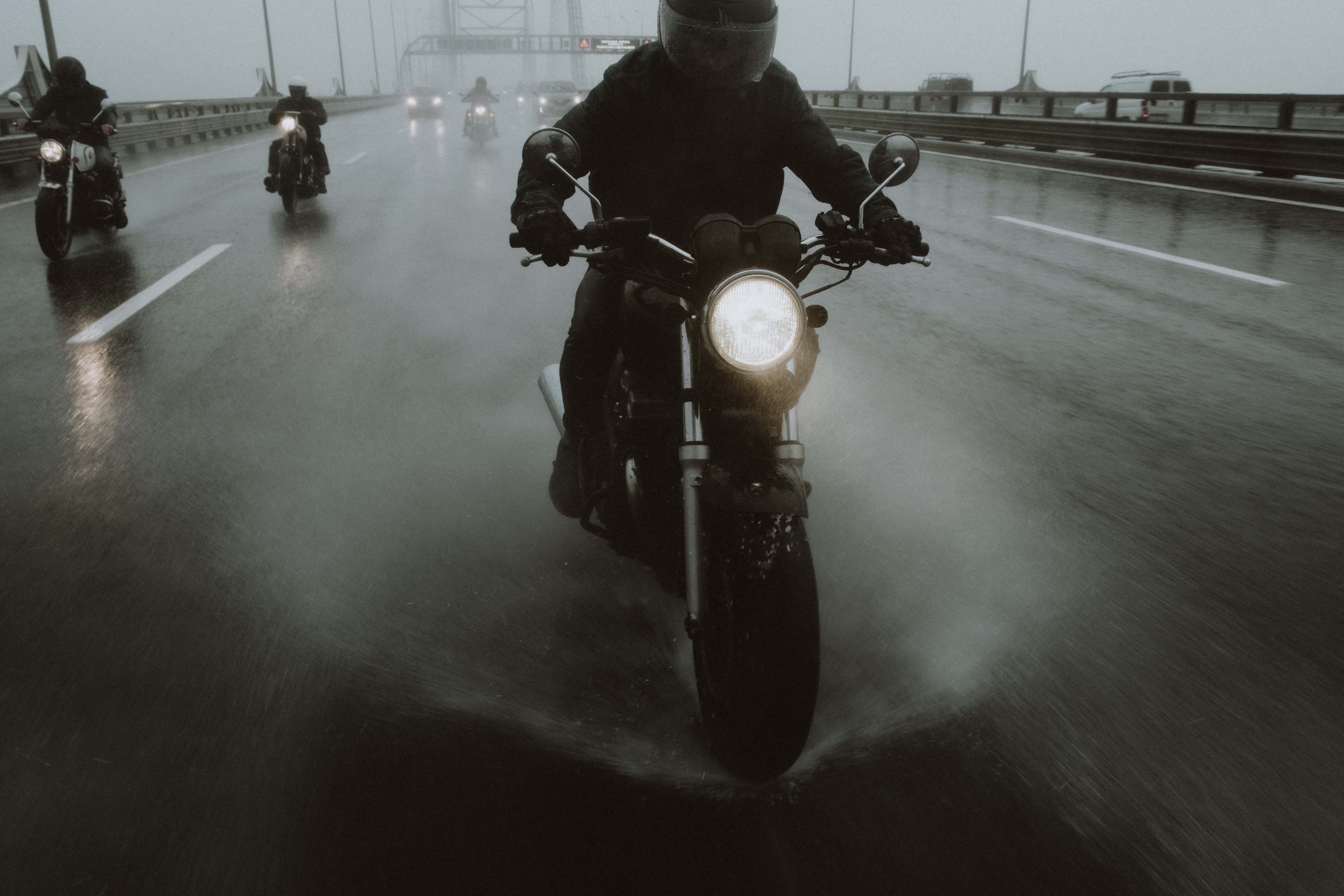 road trip 桌布 壁紙 — 摩托車騎士在滂沱大雨中行駛在濕滑的高速公路上，車頭燈劃破迷霧籠罩的昏暗。