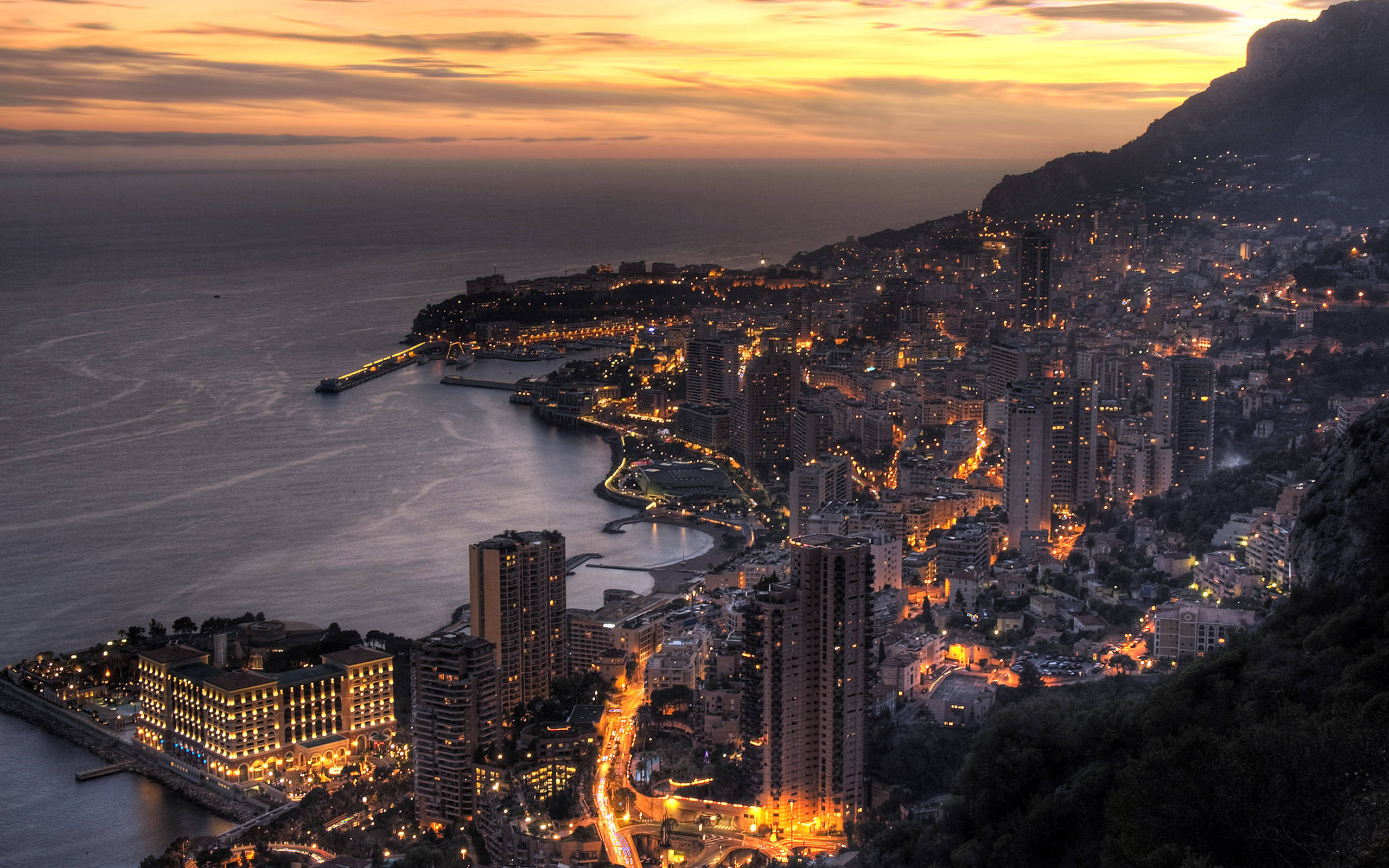Monaco 桌布 壁紙 — 摩納哥令人嘆為觀止的日落，閃爍的城市燈光擁抱著海岸線和山腰。