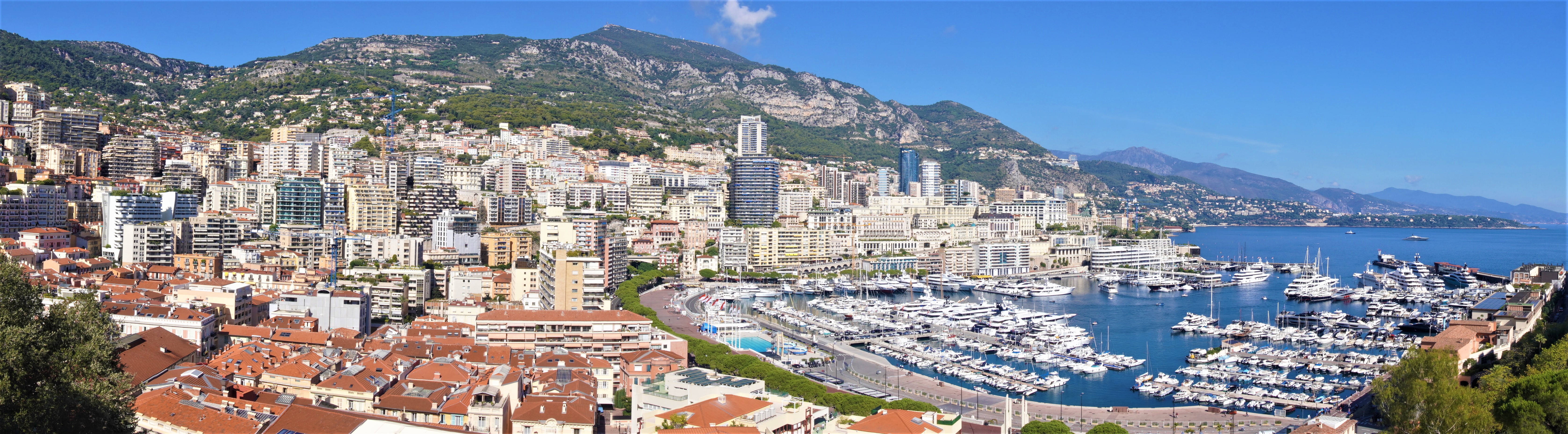 Monaco 桌布 壁紙 — 摩納哥海岸城市全景，擁有陶土屋頂、港口豪華遊艇，以及晴朗藍天下陽光普照的山脈。