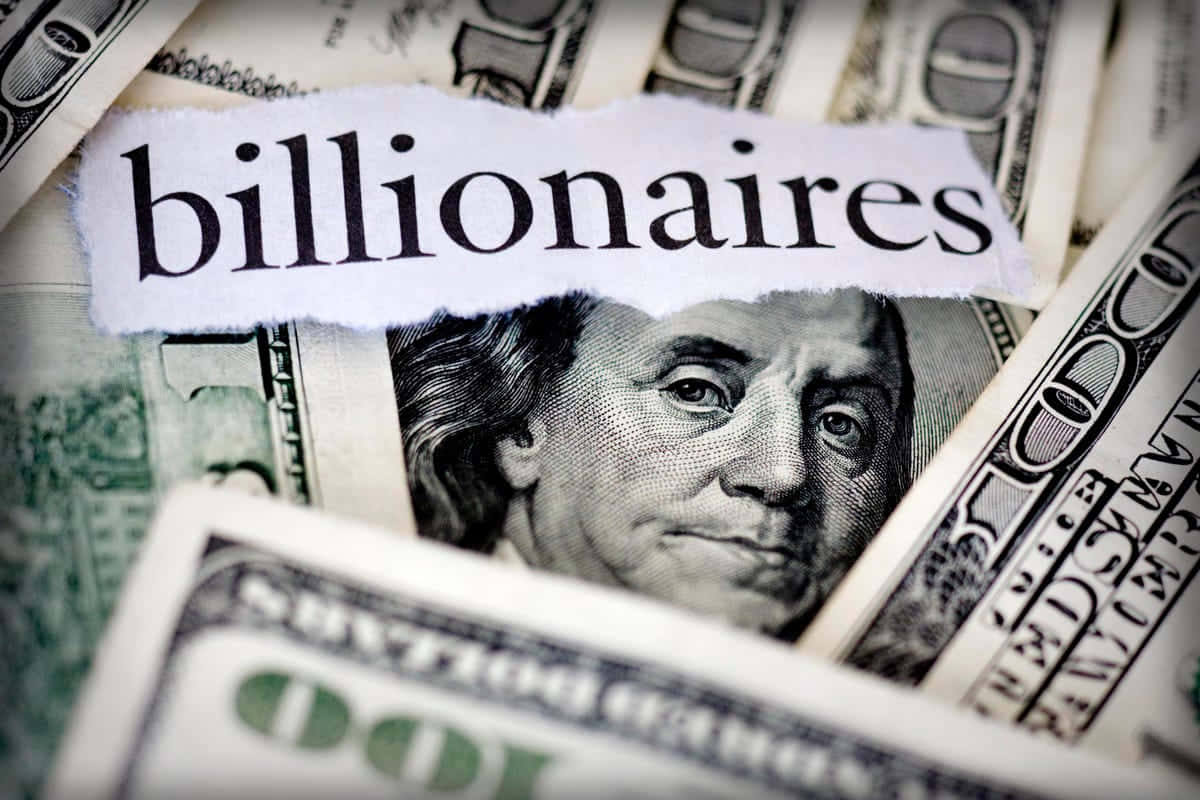 Money Motivation 桌布 壁紙 — 撕破的紙張上寫著「億萬富翁」，揭示了班傑明·富蘭克林的面孔在一堆美元鈔票上。
