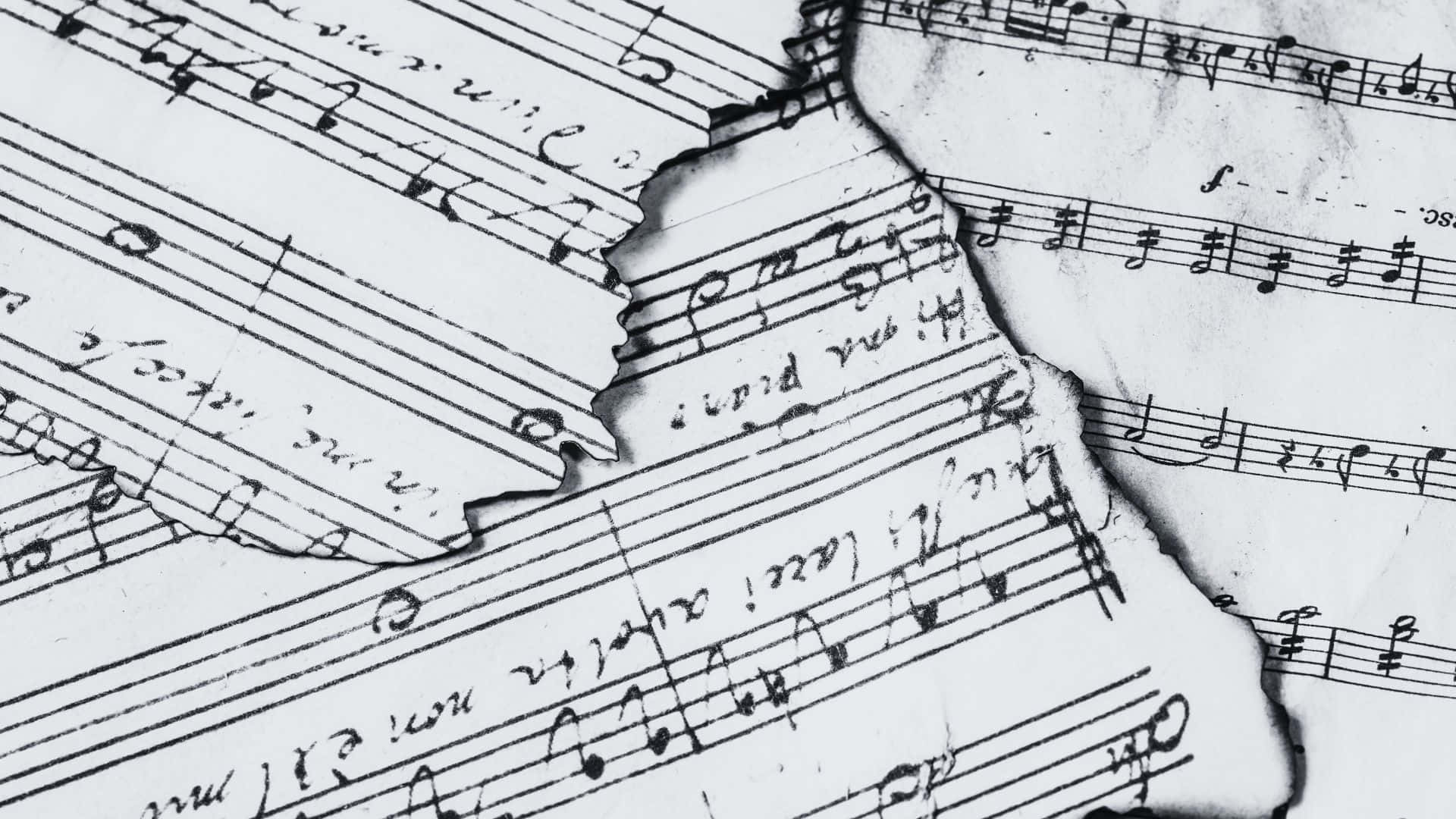 Black And White Music 桌布 壁紙 — 撕裂的復古樂譜碎片，帶有手寫音符和五線譜，單色，顯示磨損痕跡。