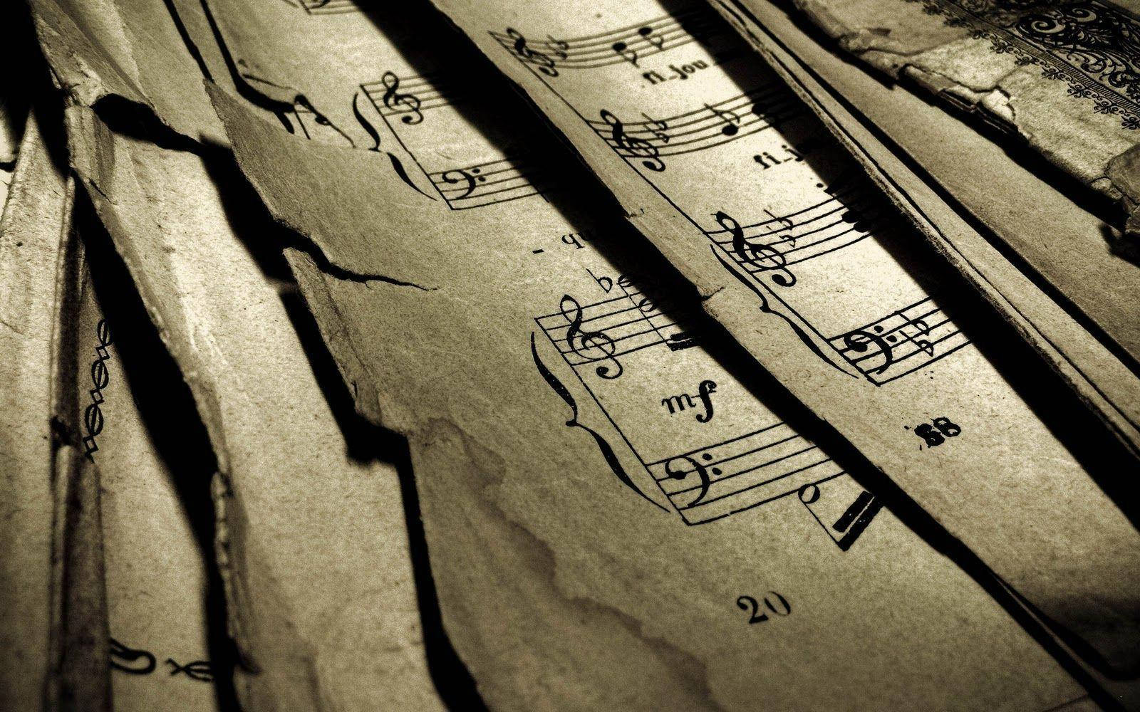 Beautiful Music 桌布 壁紙 — 撕裂的復古樂譜頁面，帶有音符和褪色墨水，處於戲劇性的陰影和光線中。