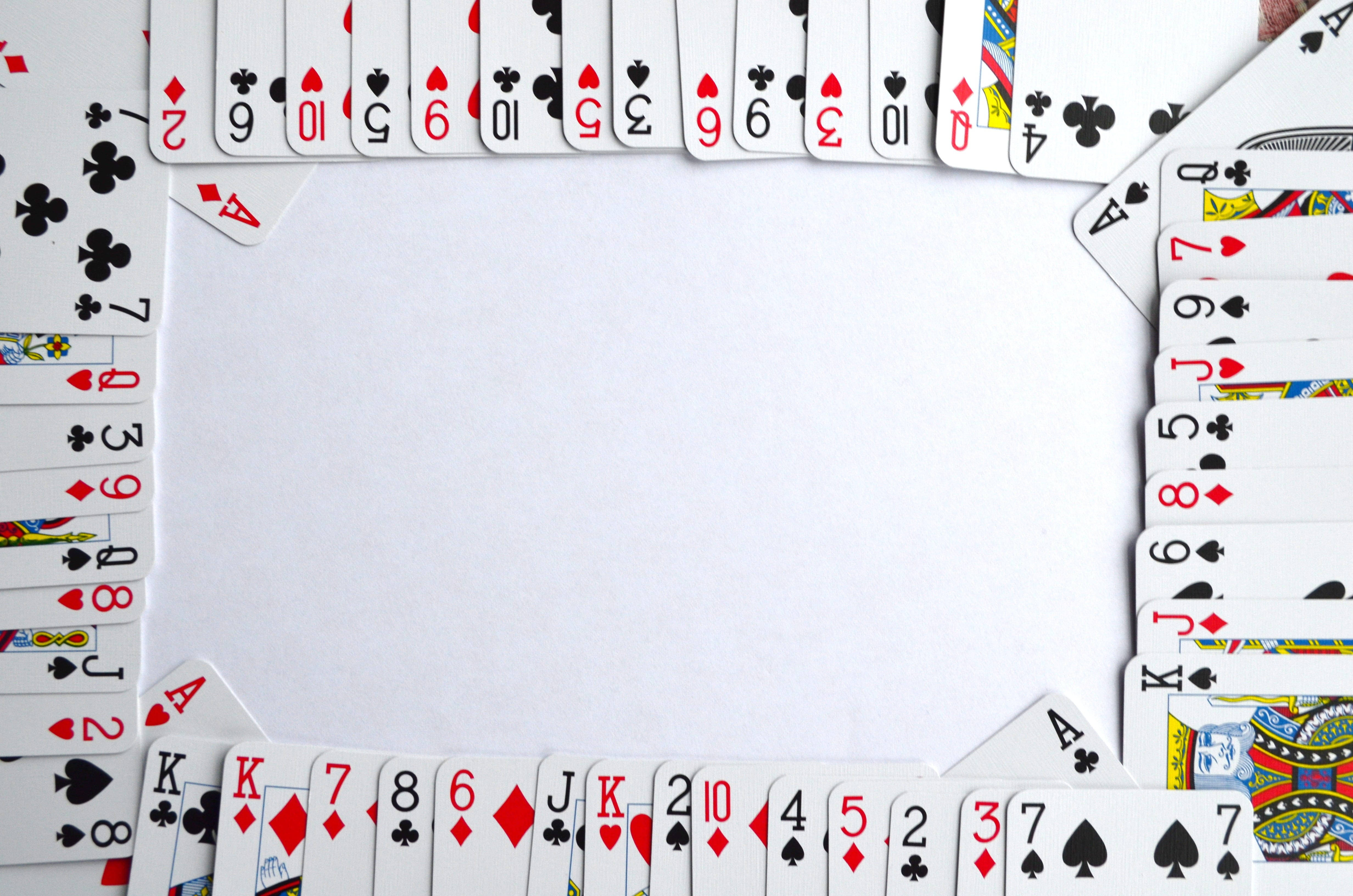Playing Cards 桌布 壁紙 — 撲克牌在平坦表面上圍繞空白白色中心排列成邊框框架。