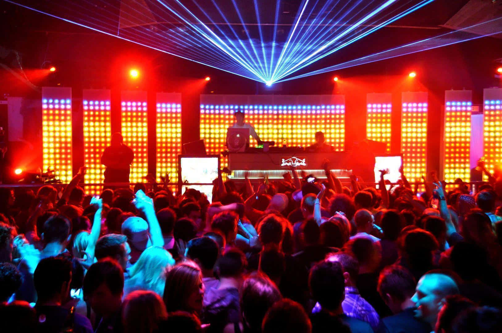 Nightclub 桌布 壁紙 — 擁擠的夜店人群在鮮豔的紅色和藍色雷射燈光及發光LED面板下跳舞。