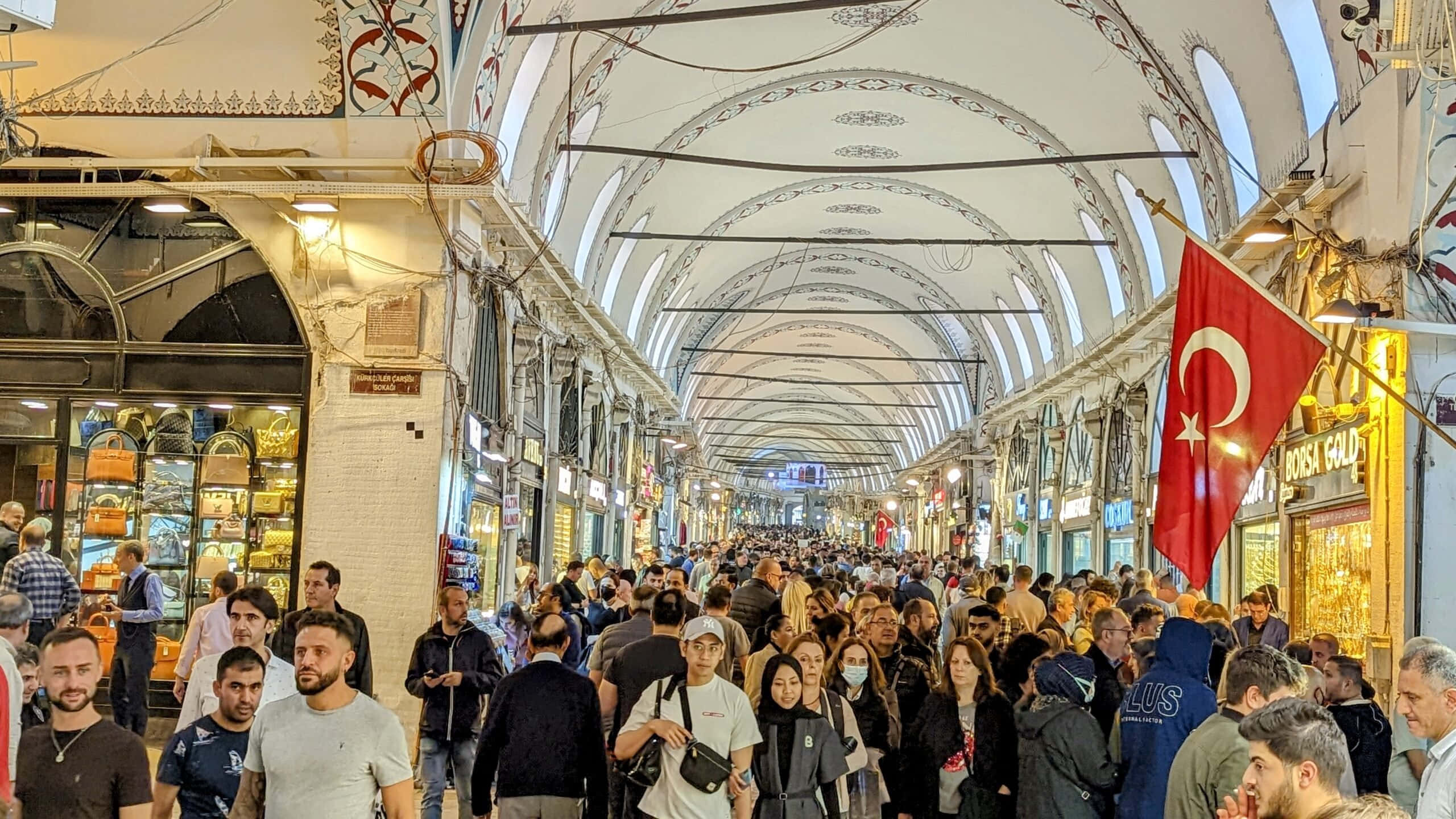 Market 桌布 壁紙 — 擁擠繁忙的室內市場，拱形天花板，土耳其國旗懸掛在頭頂，購物者穿過狹窄的通道。