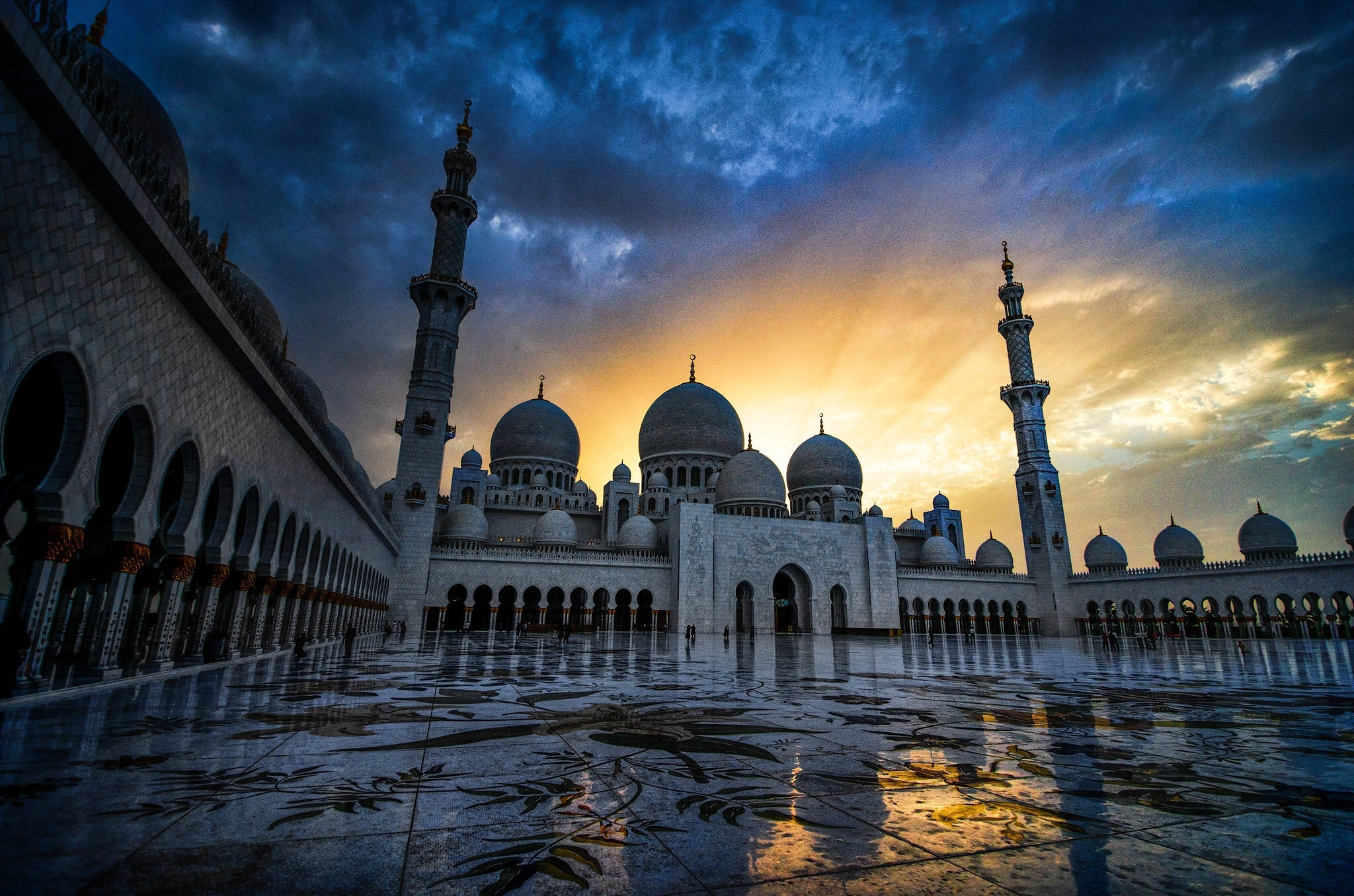 Arab 桌布 壁紙 — 擁有圓頂和宣禮塔的大清真寺在戲劇性的日落天空下倒映在濕潤的大理石庭院中。