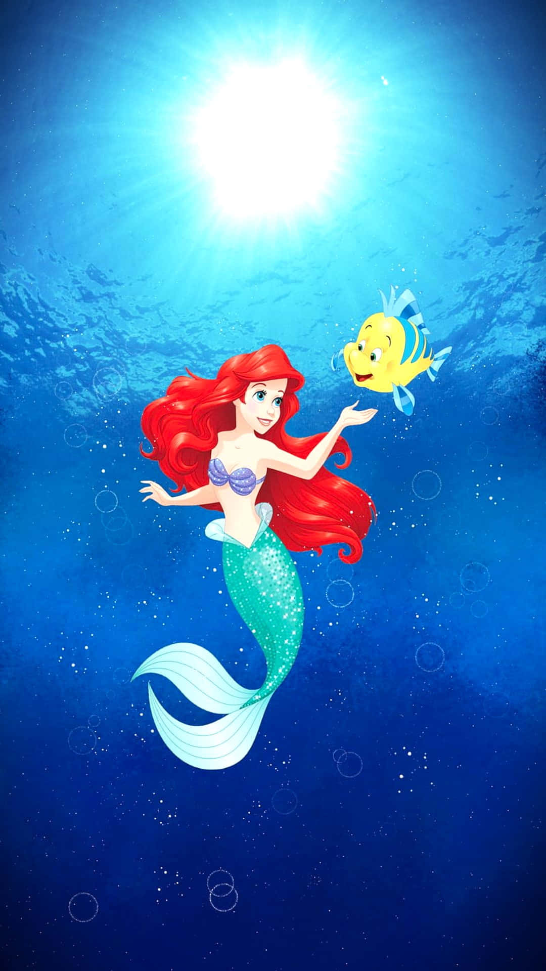 The Little Mermaid 桌布 壁紙 — 擁有飄逸紅髮和藍綠色尾巴的美人魚愛麗兒，在陽光照射的水面附近與她的黃色魚朋友快樂地游泳。