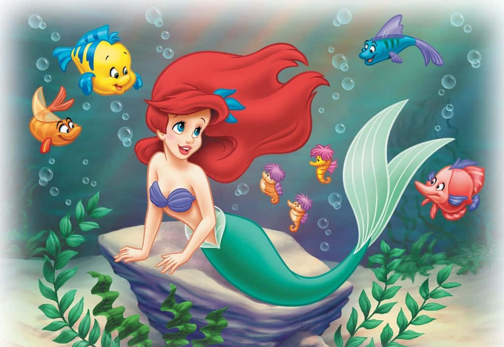 little mermaid 桌布 壁紙 — 擁有飄逸紅髮的美人魚愛麗兒坐在岩石上，周圍是色彩繽紛的魚和氣泡，構成一個海底場景。