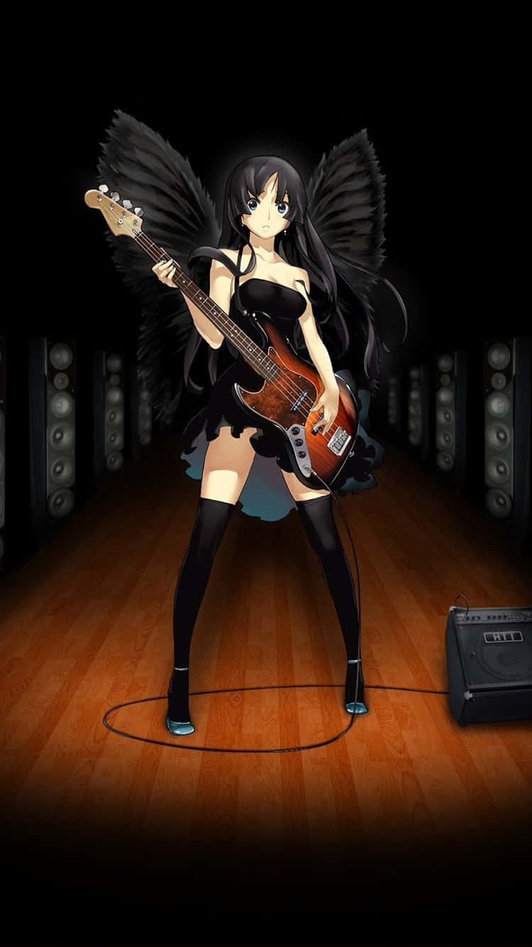 mio akiyama 桌布 壁紙 — 擁有黑色翅膀的動漫女孩在光線昏暗、鋪有木地板和喇叭堆疊的錄音室中彈奏電貝斯。