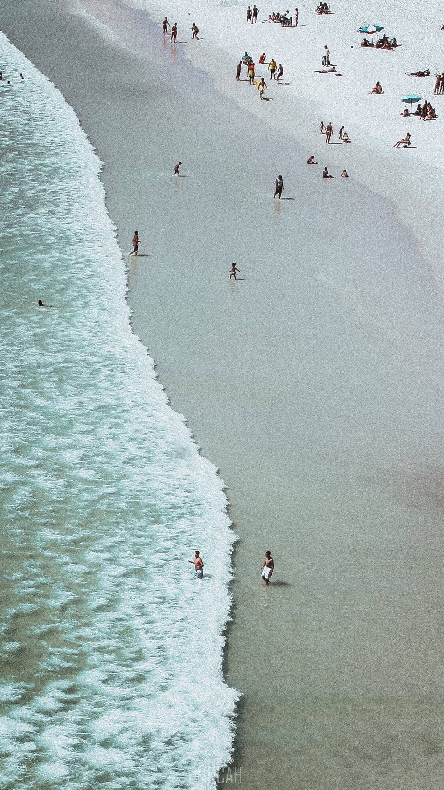 海灘 桌布 壁紙 — 擠滿人群的海灘鳥瞰圖，綠松石色的海浪拍打著海岸，人們在游泳和曬太陽。